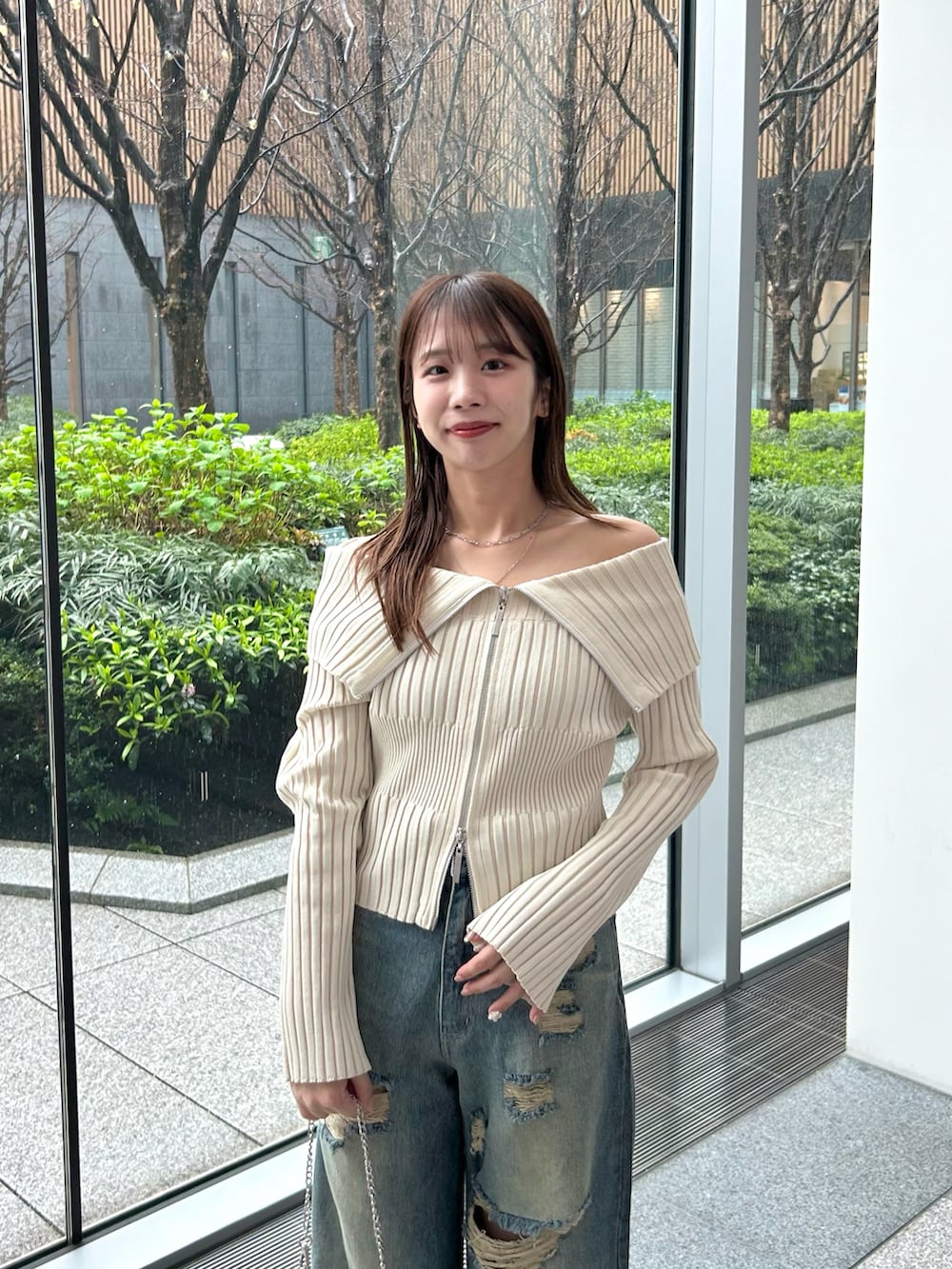 ホワイト系のニット/セーター、ブルー系のデニムパンツ、シルバー系のショルダーバッグを着用したレディースの春コーディネートの4枚目の写真