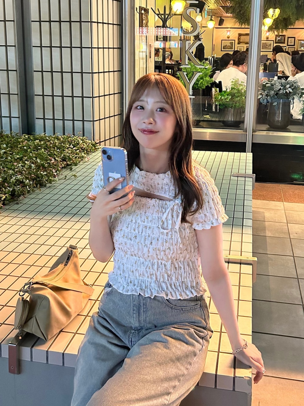 ブルー系のデニムパンツ、ホワイト系のTシャツ/カットソー、ベージュ系のショルダーバッグを着用したレディースの夏コーディネートの5枚目の写真
