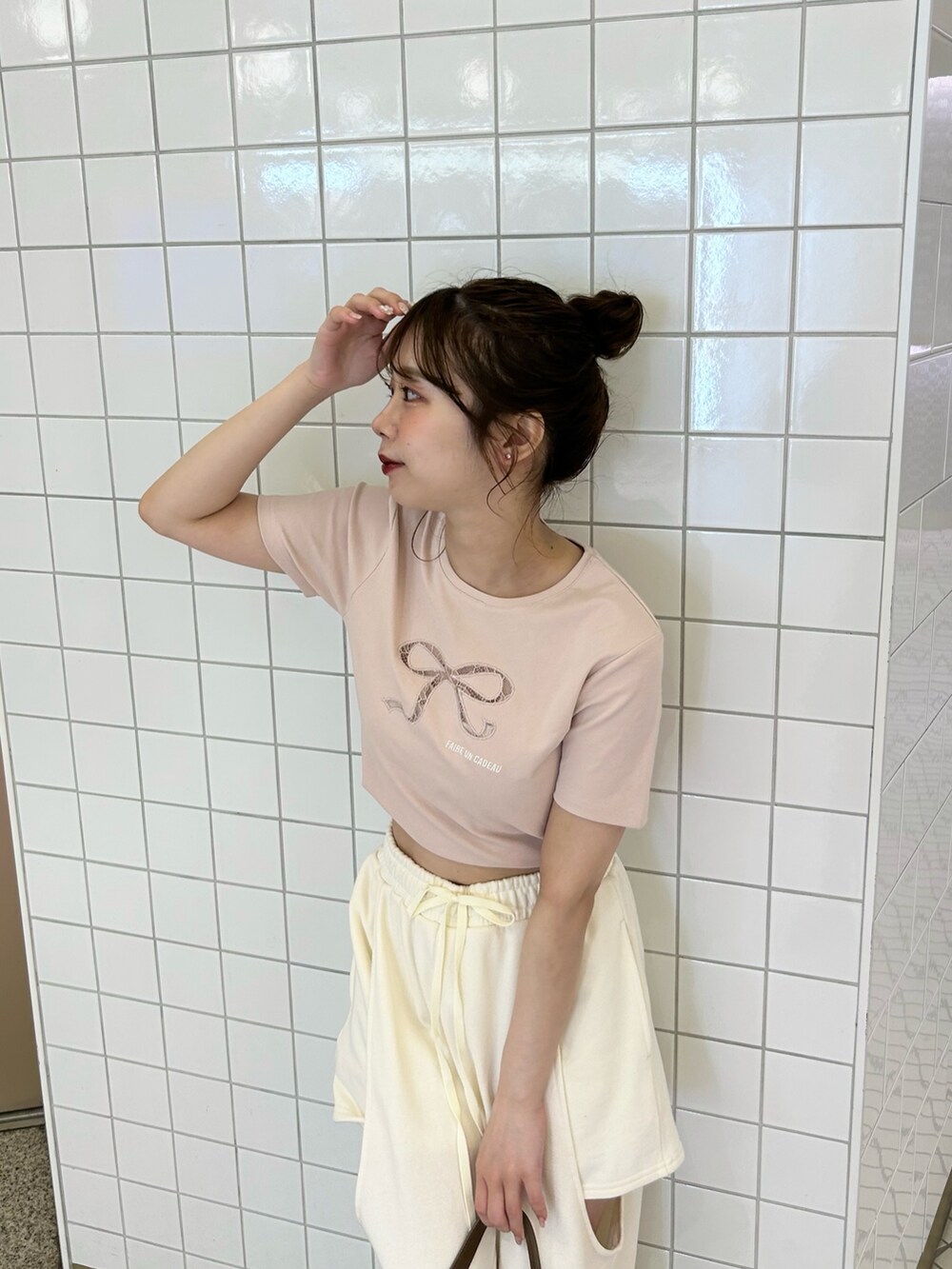 ホワイト系のパンツ、ピンク系のTシャツ/カットソー、ブラウン系のショルダーバッグを着用したレディースの春コーディネートの2枚目の写真