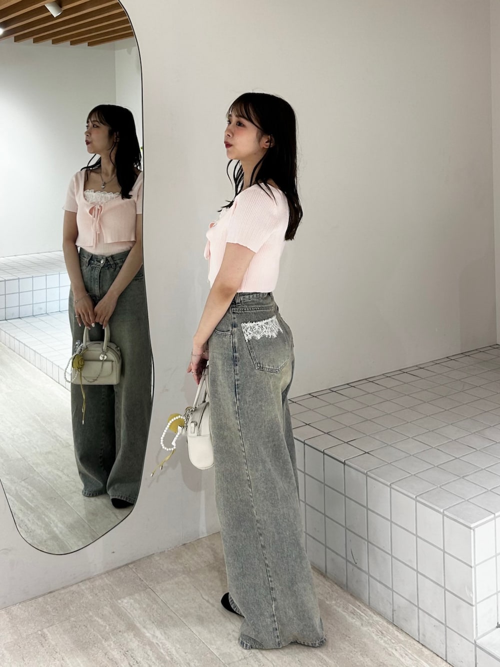 ブルー系のデニムパンツ、ホワイト系のボストンバッグ、ピンク系のカーディガン/ボレロを着用したレディースの夏コーディネートの4枚目の写真