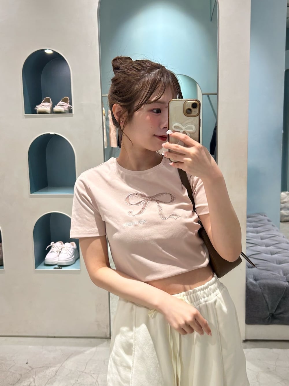 ホワイト系のパンツ、ピンク系のTシャツ/カットソー、ブラウン系のショルダーバッグを着用したレディースの春コーディネートの3枚目の写真