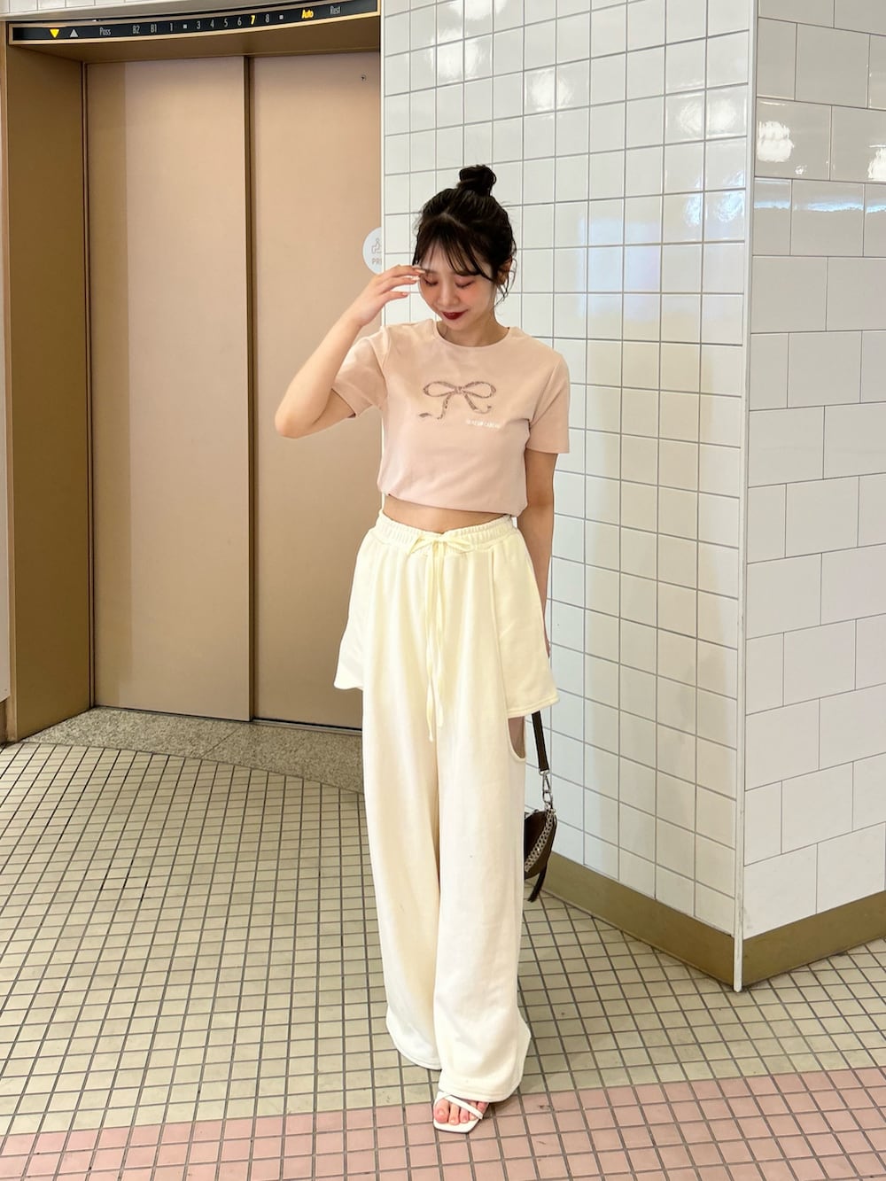ホワイト系のパンツ、ピンク系のTシャツ/カットソー、ブラウン系のショルダーバッグを着用したレディースの春コーディネートの4枚目の写真