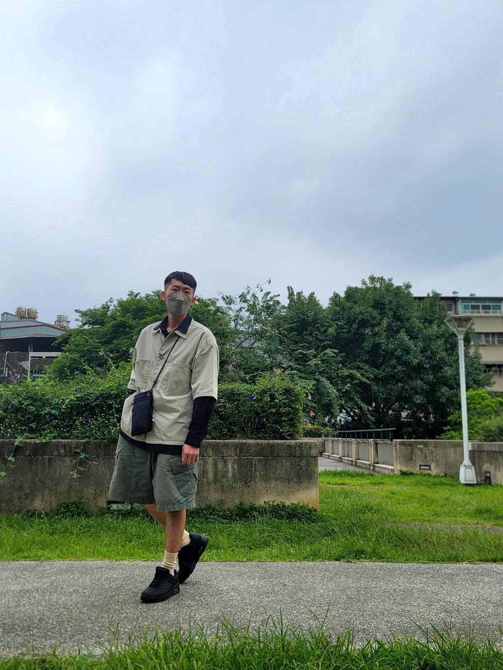 グリーン系のカーゴパンツ、ブラック系のスニーカー、ブラック系のシャツ/ブラウスを着用したメンズの春コーディネートの4枚目の写真