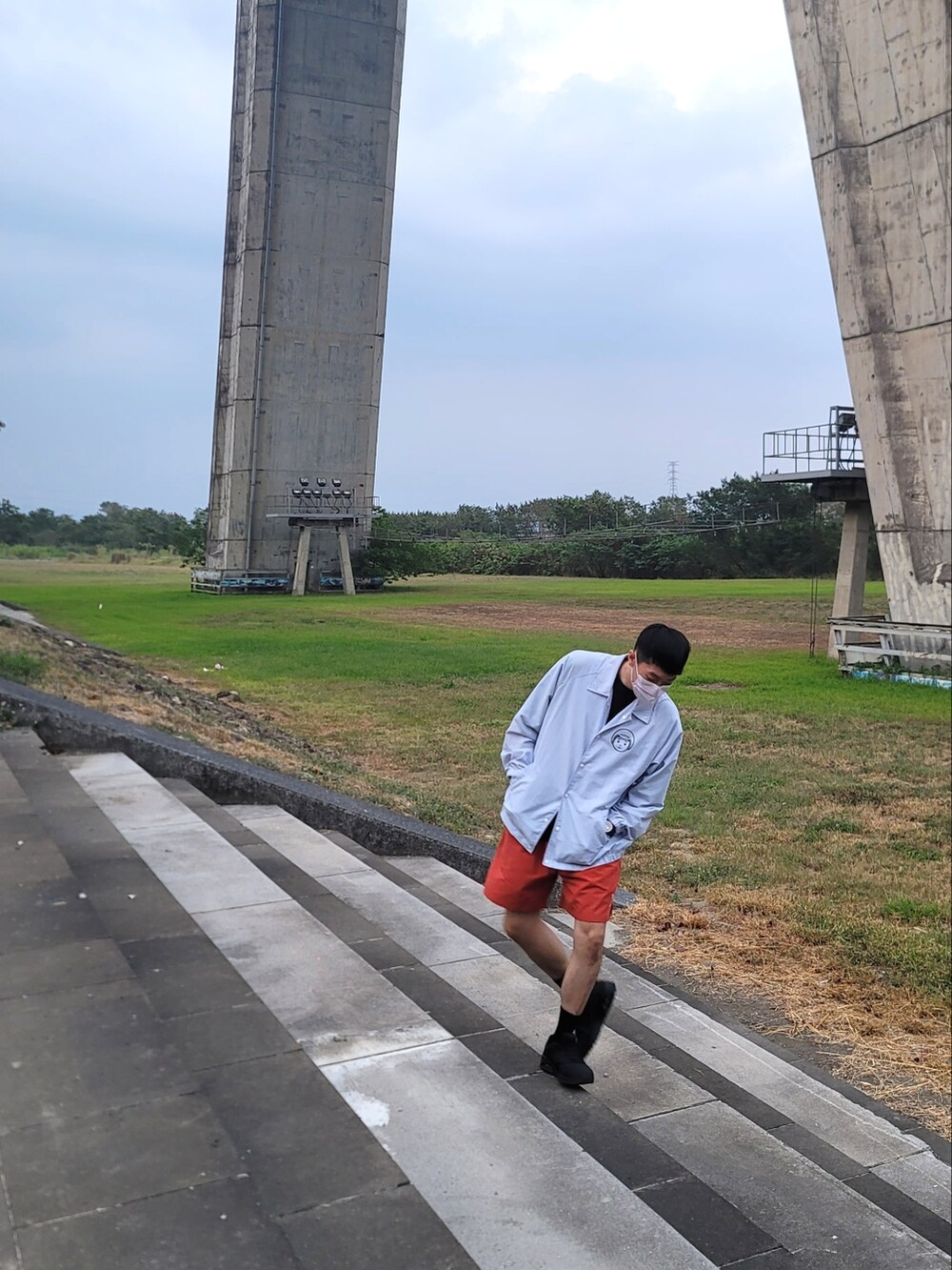 ブラック系のスニーカー、オレンジ系のカーゴパンツ、ブルー系のライダースジャケットを着用したメンズの春コーディネートの3枚目の写真