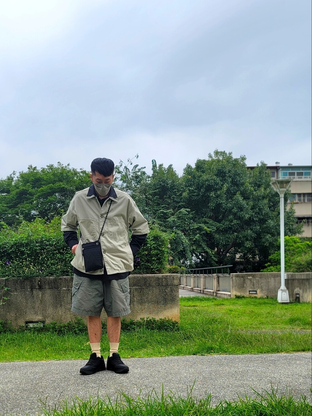 グリーン系のカーゴパンツ、ブラック系のスニーカー、ブラック系のシャツ/ブラウスを着用したメンズの春コーディネートの2枚目の写真
