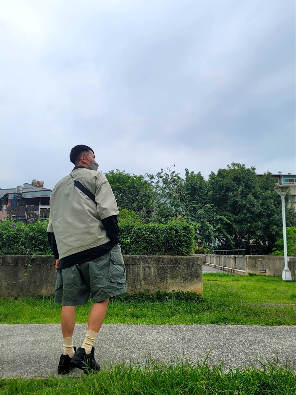 グリーン系のカーゴパンツ、ブラック系のスニーカー、ブラック系のシャツ/ブラウスを着用したメンズの春コーディネートの3枚目の写真