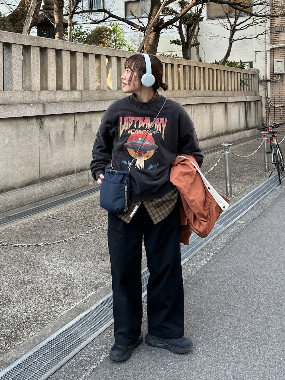 ブラック系のその他パンツ、オレンジ系のマウンテンパーカー、ブルー系のショルダーバッグを着用したレディースの冬コーディネートの2枚目の写真