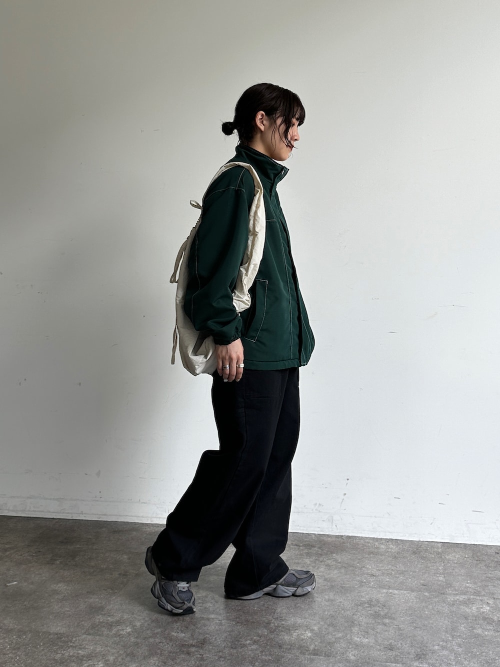 ブラック系のその他パンツ、グリーン系のブルゾン、ホワイト系のバックパック/リュックを着用したレディースの秋コーディネートの2枚目の写真