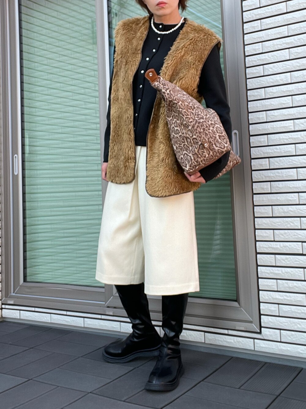 ブラウン系のベスト、ブラック系のカーディガン/ボレロ、ブラウン系のハンドバッグを着用したレディースの秋コーディネートの2枚目の写真