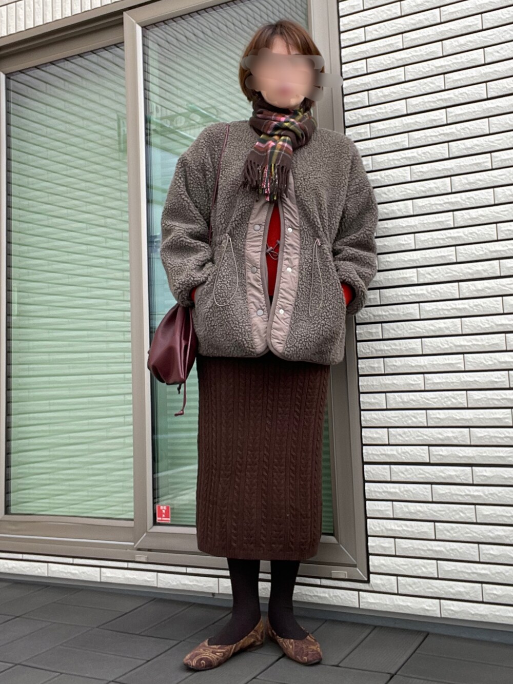 ブラウン系のブルゾン、ブラウン系のニット/セーター、レッド系のクラッチバッグを着用したレディースの秋コーディネートの2枚目の写真