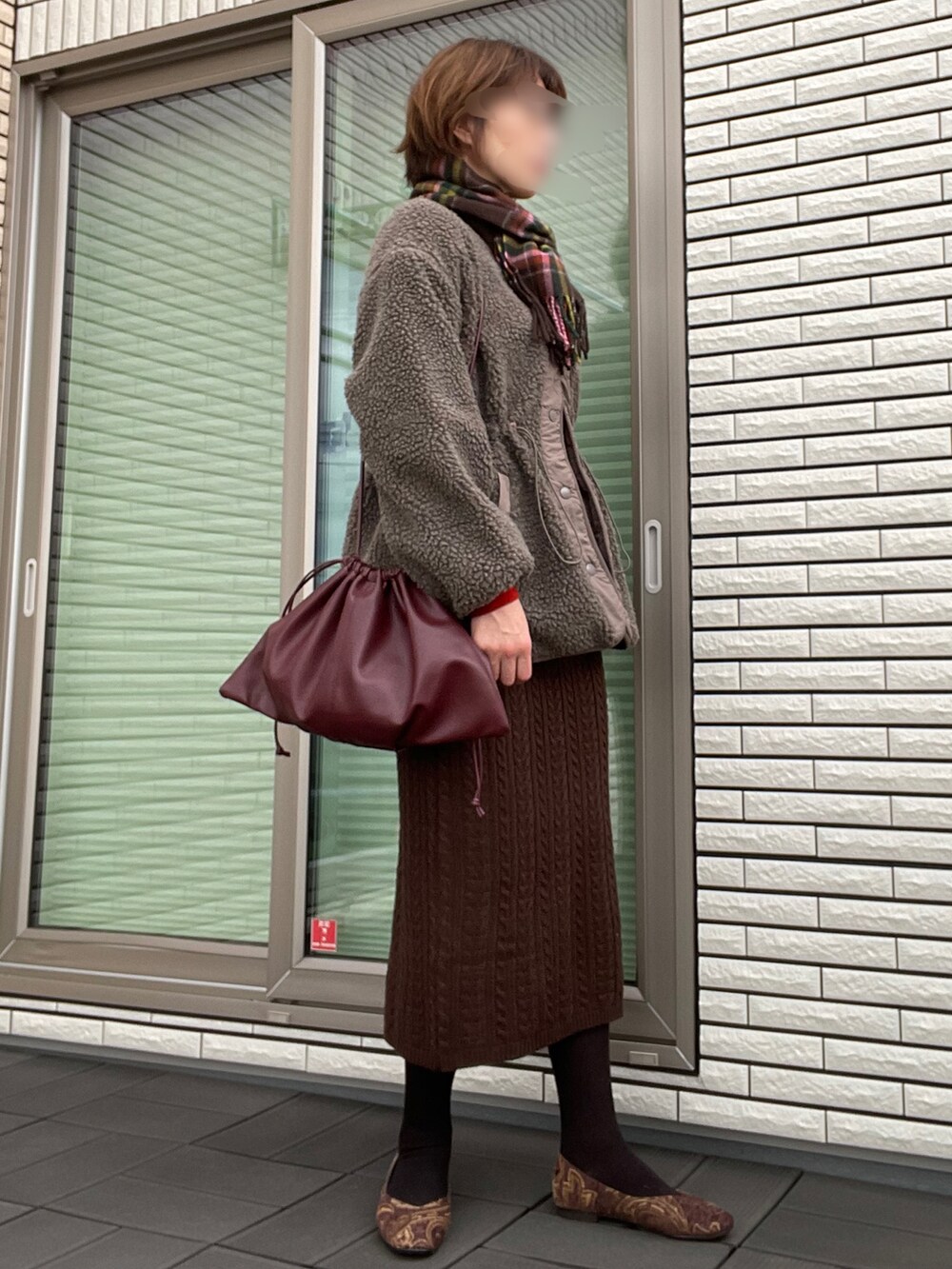 ブラウン系のブルゾン、ブラウン系のニット/セーター、レッド系のクラッチバッグを着用したレディースの秋コーディネートの3枚目の写真
