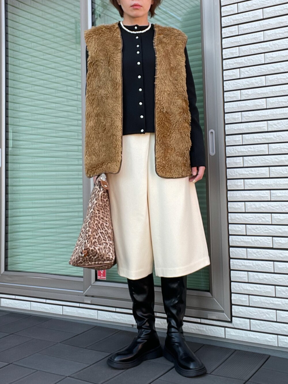 ブラウン系のベスト、ブラック系のカーディガン/ボレロ、ブラウン系のハンドバッグを着用したレディースの秋コーディネートの3枚目の写真
