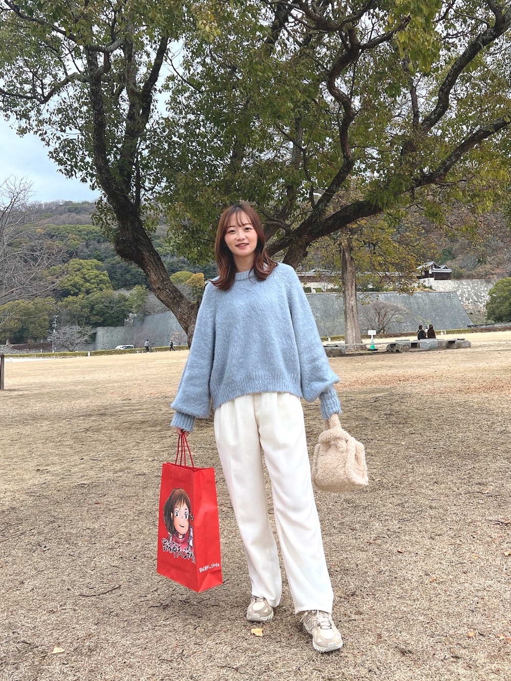 ブルー系のニット/セーター、ホワイト系のスラックス、ベージュ系のスニーカーを着用したレディースの冬コーディネートの2枚目の写真