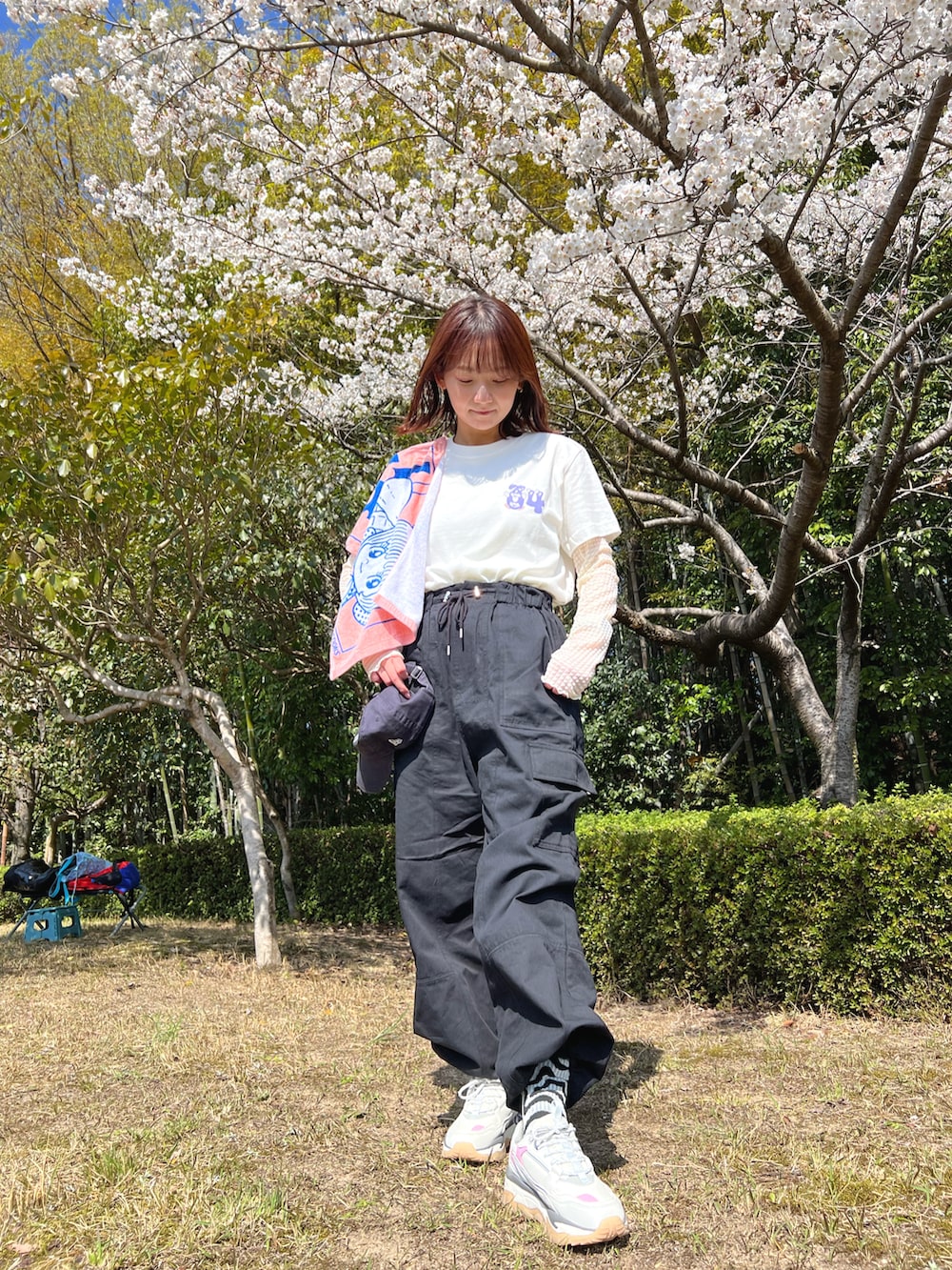 ブラック系のカーゴパンツ、ホワイト系のスニーカー、ブルー系のキャップを着用したレディースの春コーディネートの3枚目の写真