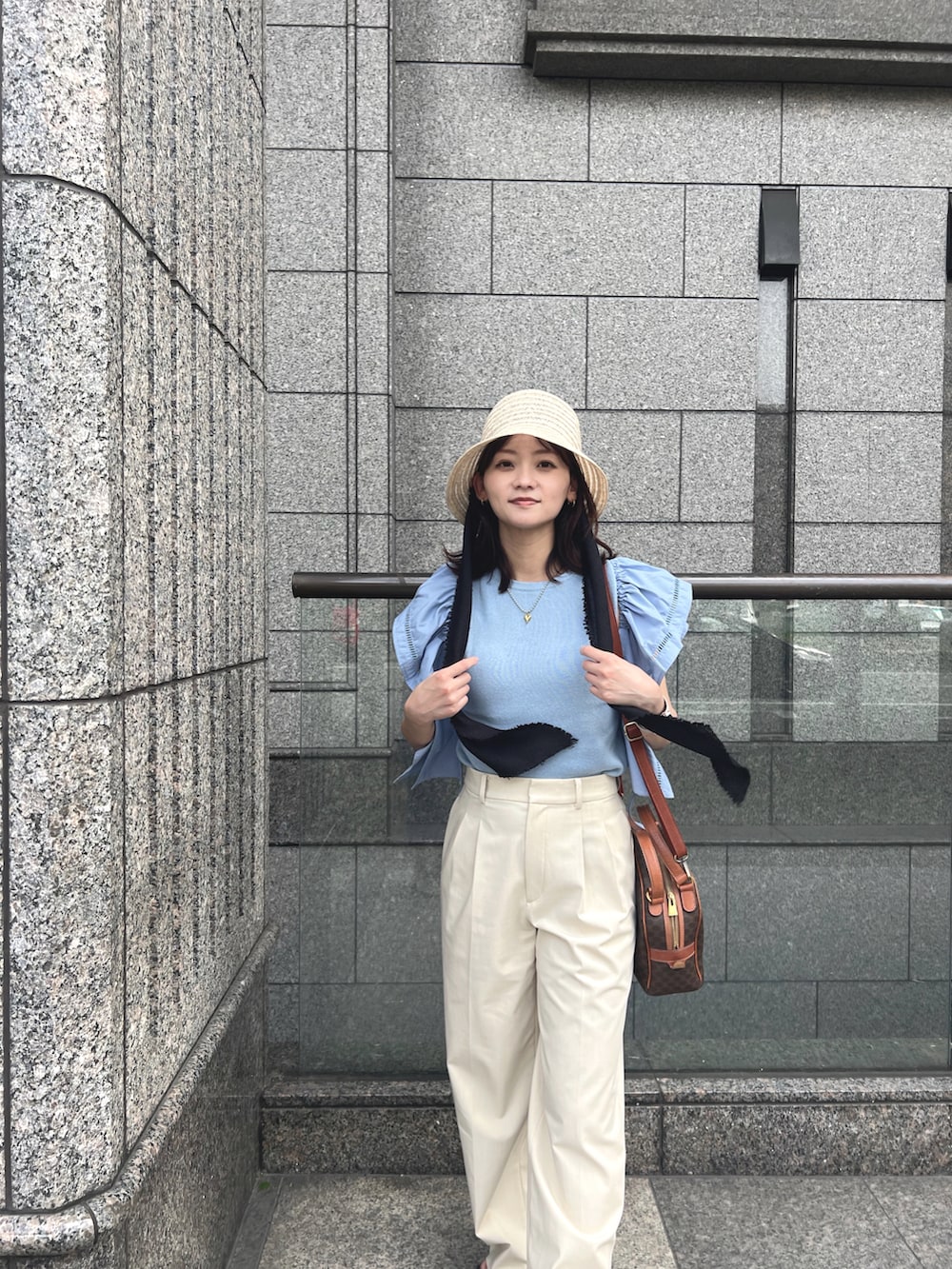 ブルー系のトップス、ブラウン系のショルダーバッグ、ホワイト系のパンツを着用したレディースの夏コーディネートの2枚目の写真