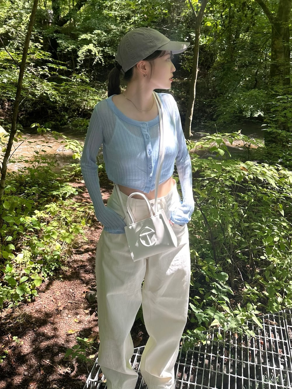 ブルー系のトップス、ホワイト系のデニムパンツ、グレー系のキャップを着用したレディースの夏コーディネートの2枚目の写真