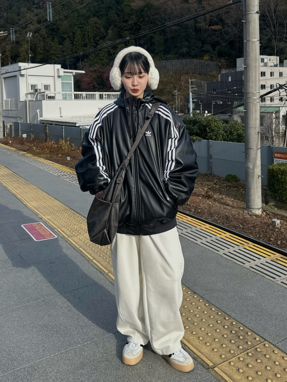 ブラック系のブルゾン、ホワイト系のスウェットパンツ、グレー系のショルダーバッグを着用したレディースの秋コーディネートの2枚目の写真