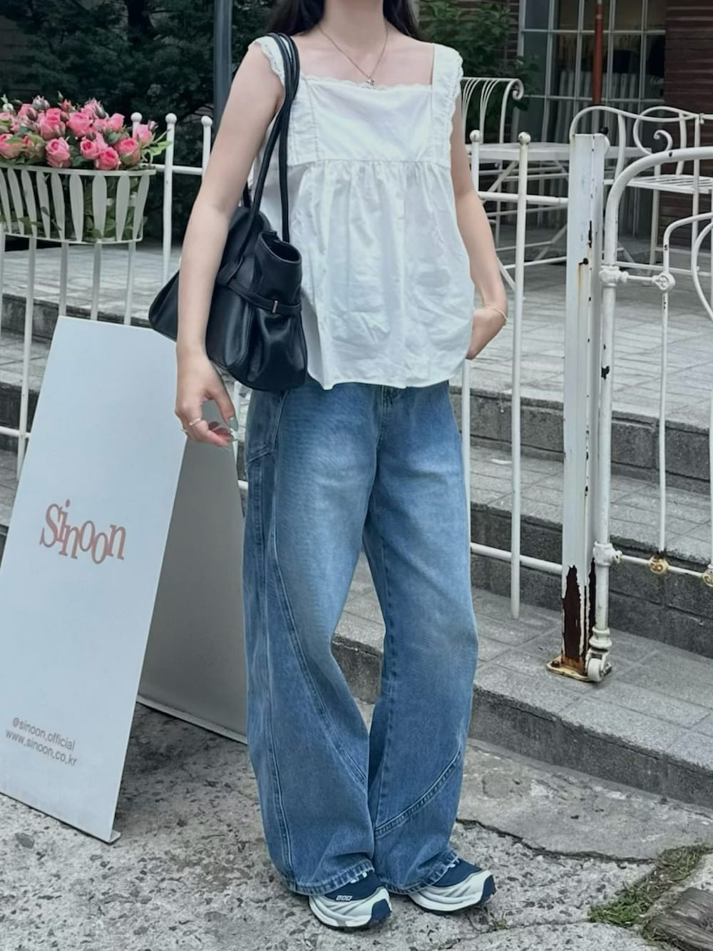 ブルー系のデニムパンツ、ブルー系のスニーカー、ブラック系のショルダーバッグを着用したレディースの夏コーディネートの2枚目の写真
