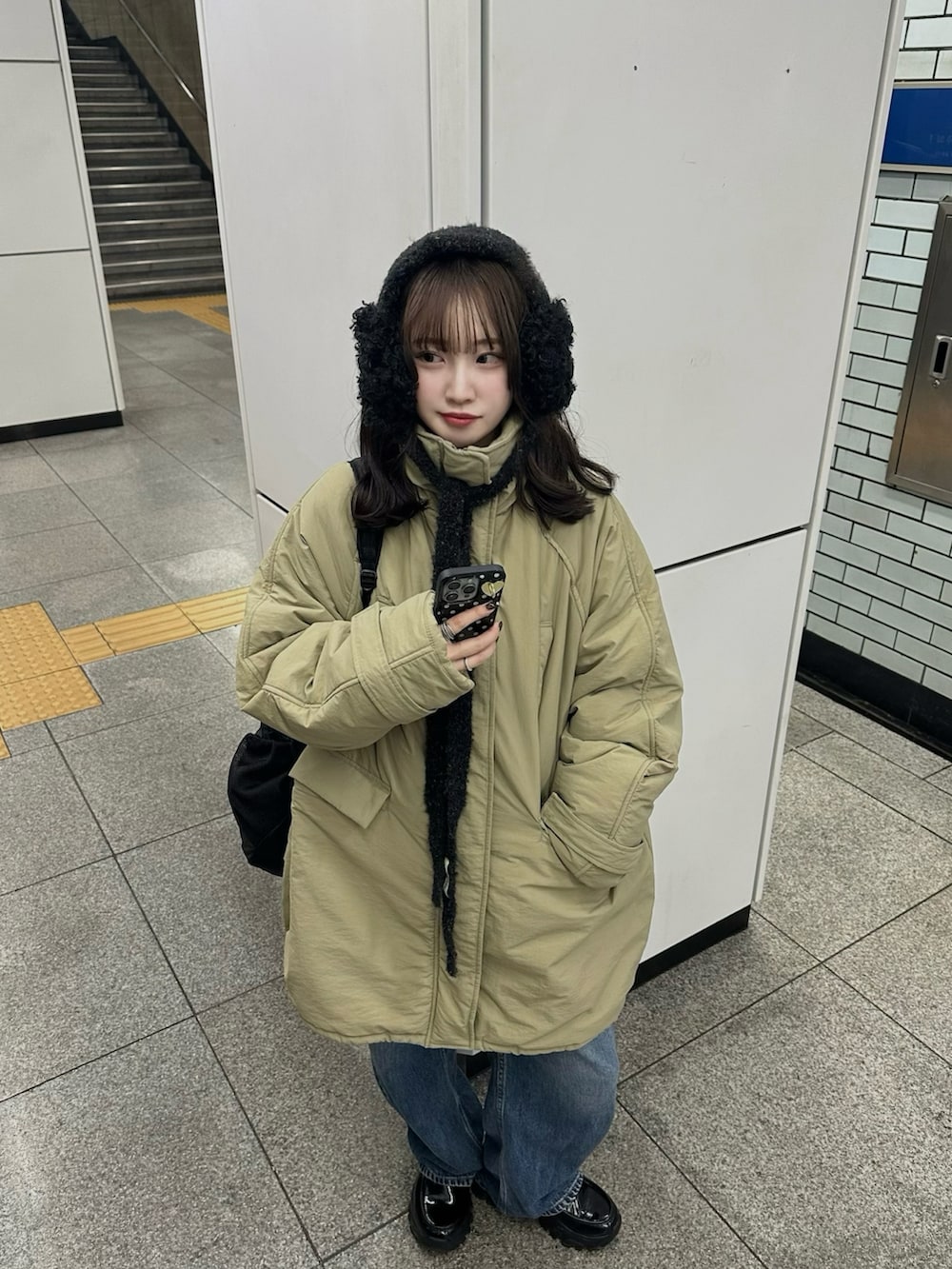 グリーン系のダウンジャケット/コート、ブラック系のローファー、ブルー系のデニムパンツを着用したレディースの春コーディネートの2枚目の写真