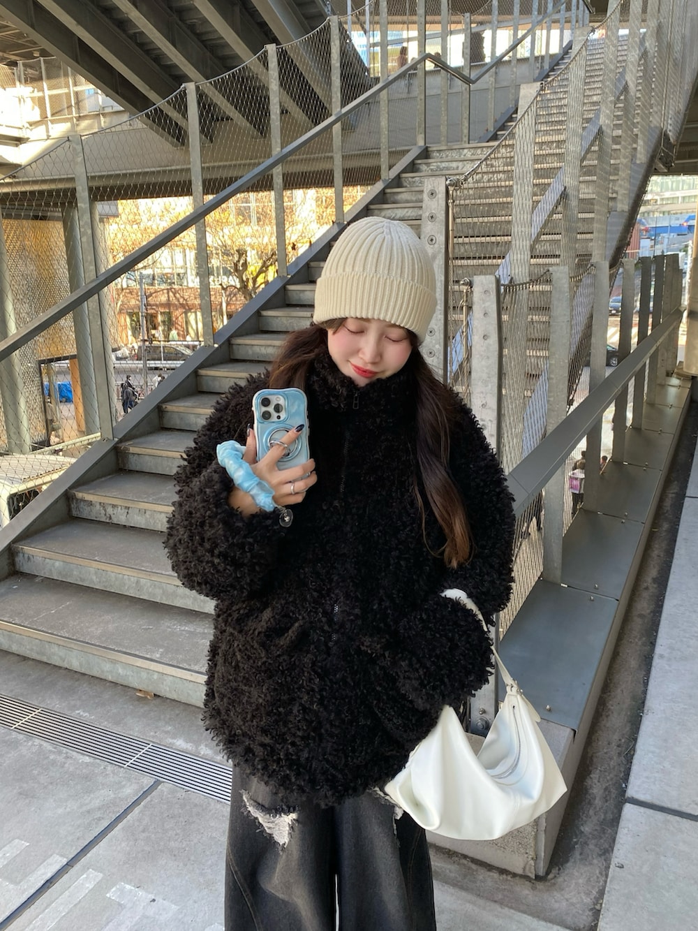 ブラック系のテーラードジャケット、ホワイト系のハンドバッグ、ホワイト系のニットキャップ/ビーニーを着用したレディースの冬コーディネートの2枚目の写真