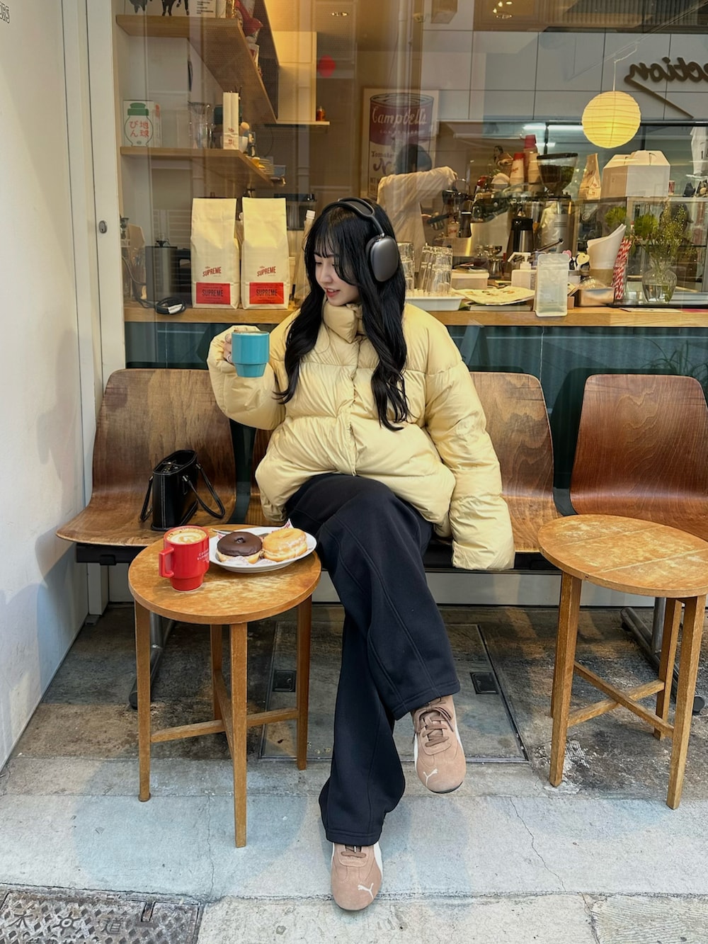 イエロー系のダウンジャケット/コート、ブラック系のスウェットパンツ、ブラック系のハンドバッグを着用したレディースの冬コーディネートの2枚目の写真