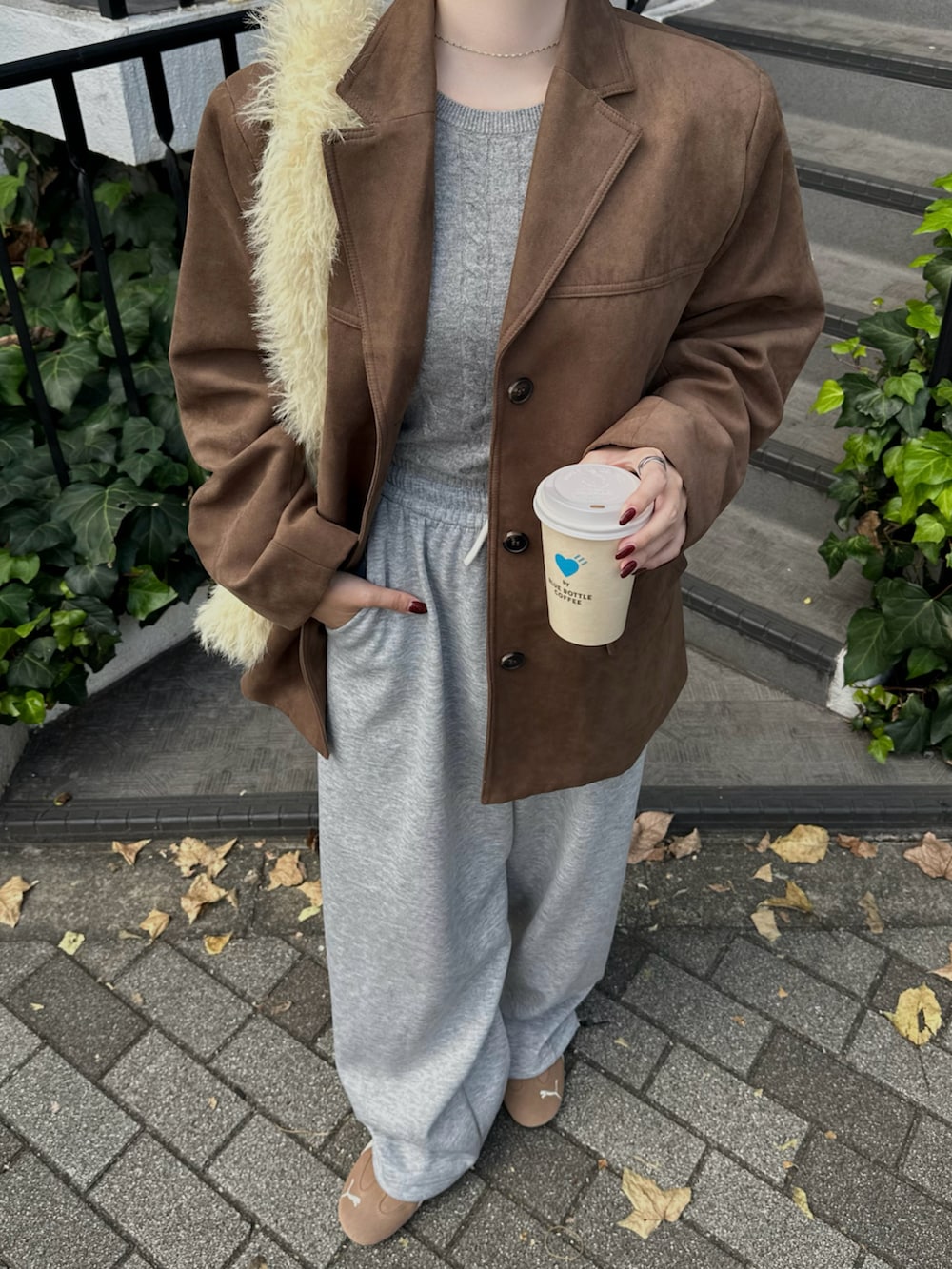 グレー系のスウェットパンツ、ブラウン系のテーラードジャケット、ブラウン系のスニーカーを着用したレディースの秋コーディネートの2枚目の写真