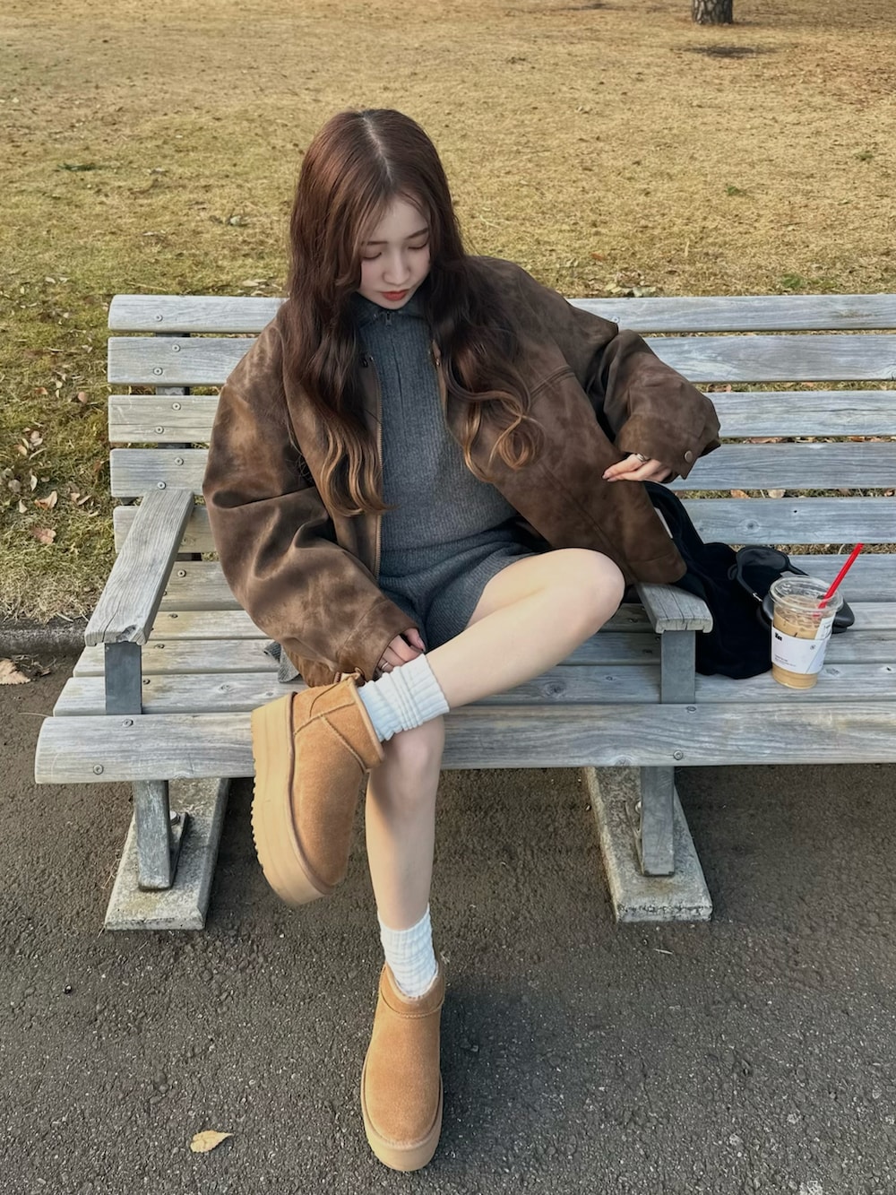 ベージュ系のブーツ、ブラウン系のライダースジャケット、グレー系のパンツを着用したレディースの冬コーディネートの2枚目の写真