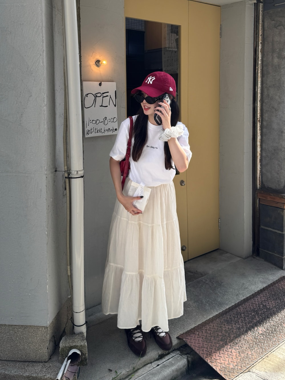 ホワイト系のTシャツ/カットソー、ホワイト系のスカート、レッド系のバッグを着用したレディースの夏コーディネートの2枚目の写真