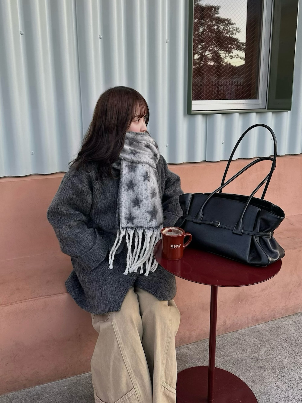 グレー系のステンカラーコート、ブラック系のショルダーバッグ、ブラック系のマフラーを着用したレディースの冬コーディネートの2枚目の写真