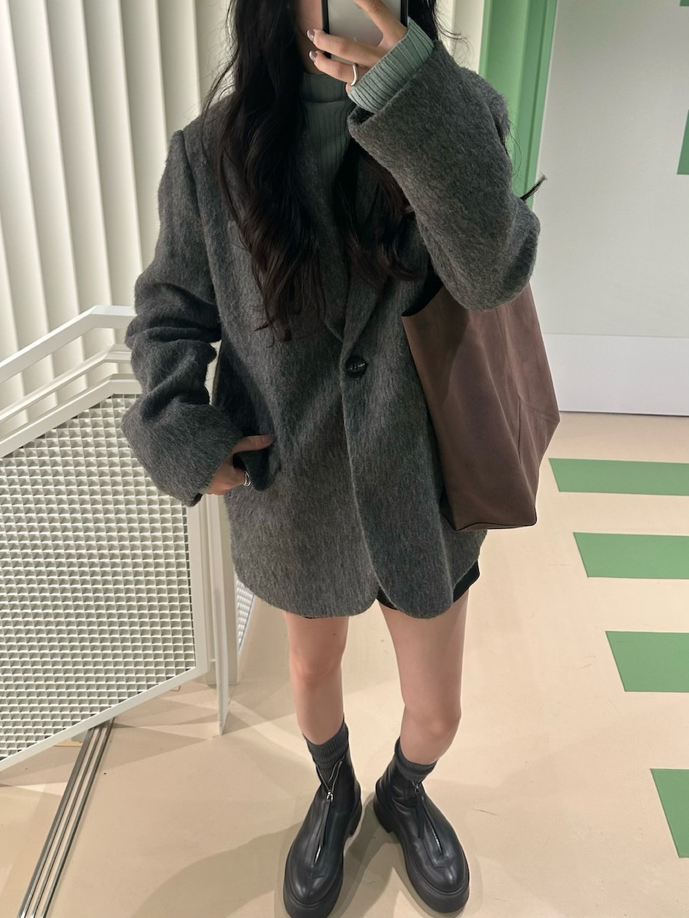 グレー系のテーラードジャケット、ブラック系のブーツを着用したレディースの秋コーディネートの2枚目の写真