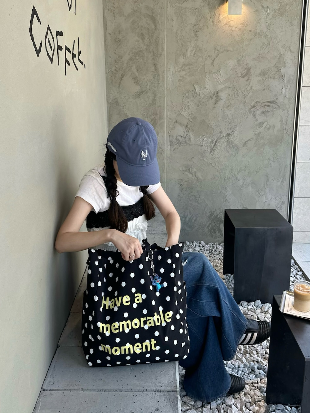 ブラック系のスニーカー、ホワイト系のトップス、ブルー系のデニムパンツを着用したレディースの夏コーディネートの2枚目の写真