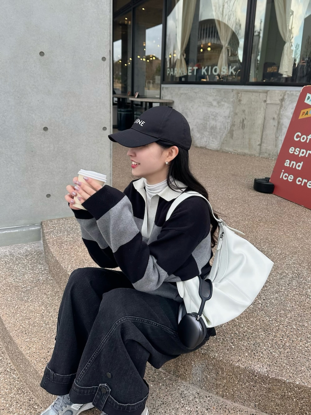 グレー系のニット/セーター、ブラック系のデニムパンツ、グレー系のスニーカーを着用したレディースの冬コーディネートの2枚目の写真