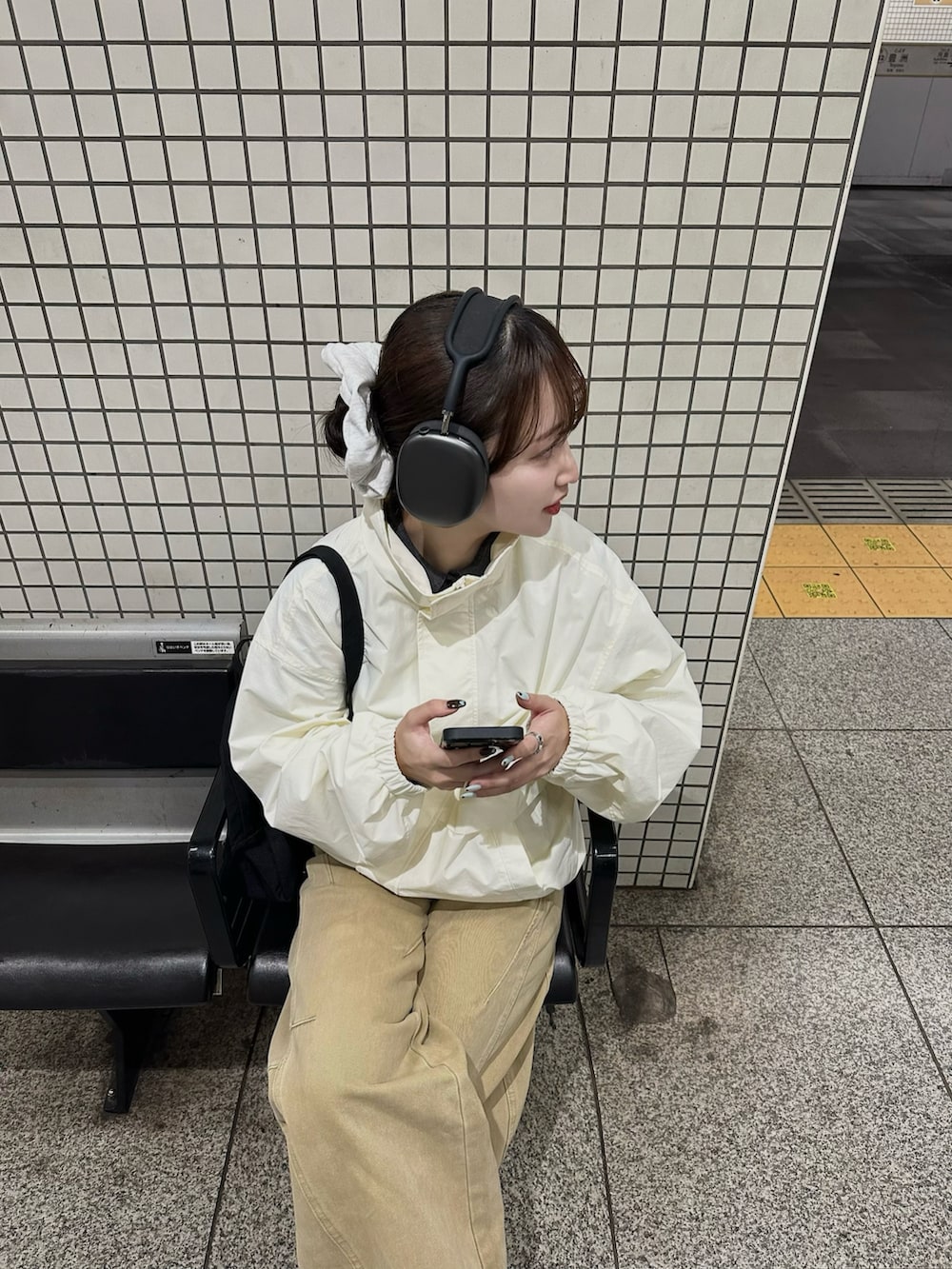 ブラック系のバックパック/リュック、ブラック系のスニーカー、ホワイト系のジャケット/アウターを着用したレディースの冬コーディネートの2枚目の写真
