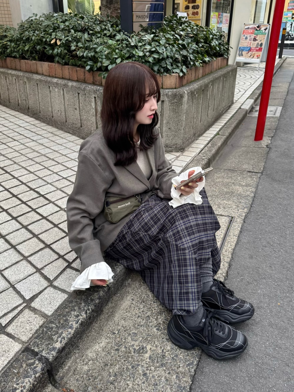 ブルー系のスカート、グレー系のテーラードジャケット、ブラック系のスニーカーを着用したレディースの春コーディネートの2枚目の写真