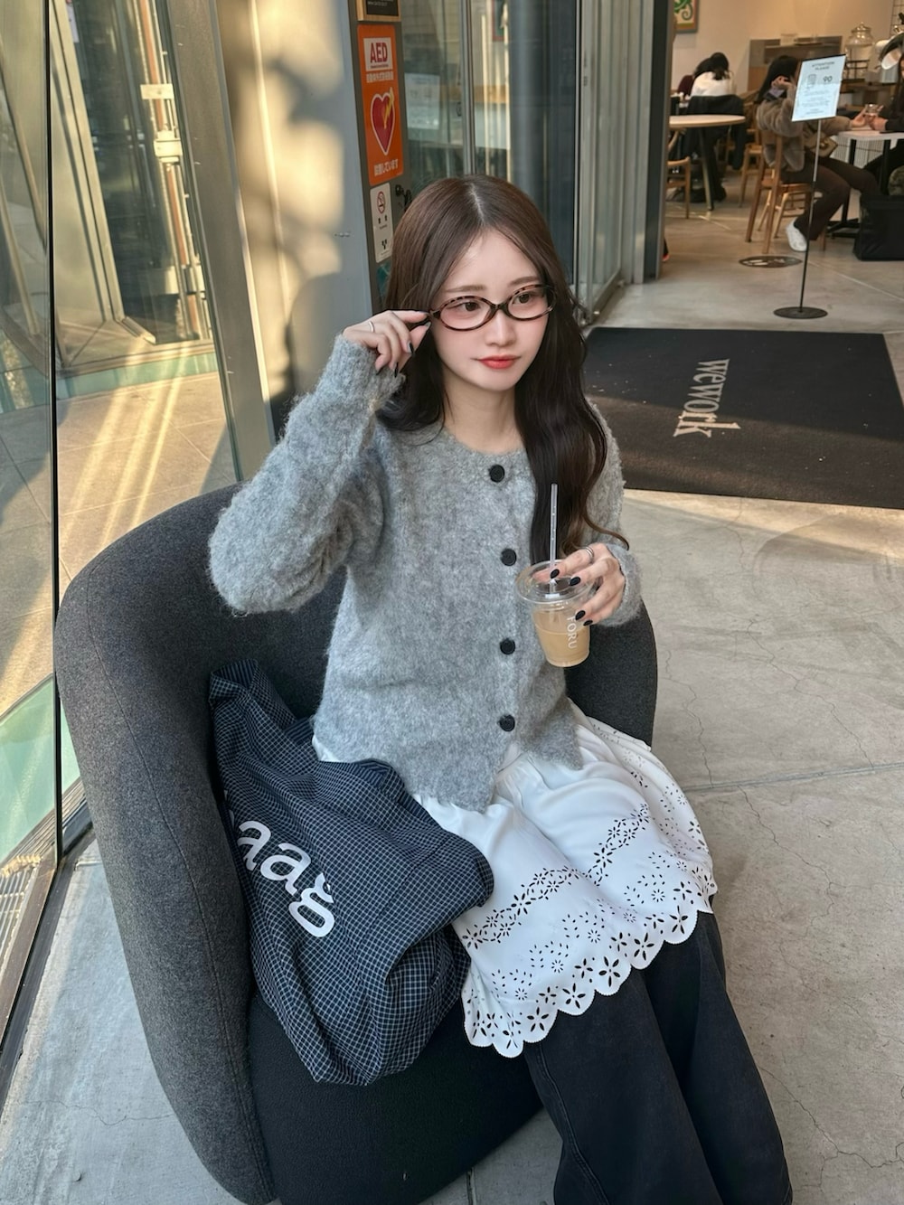 グレー系のカーディガン/ボレロ、ブラック系のデニムパンツ、ホワイト系のワンピースを着用したレディースの冬コーディネートの2枚目の写真