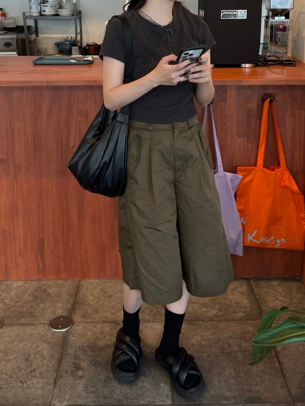 グレー系のTシャツ/カットソー、グリーン系のパンツ、ブラック系のショルダーバッグを着用したレディースの夏コーディネートの2枚目の写真
