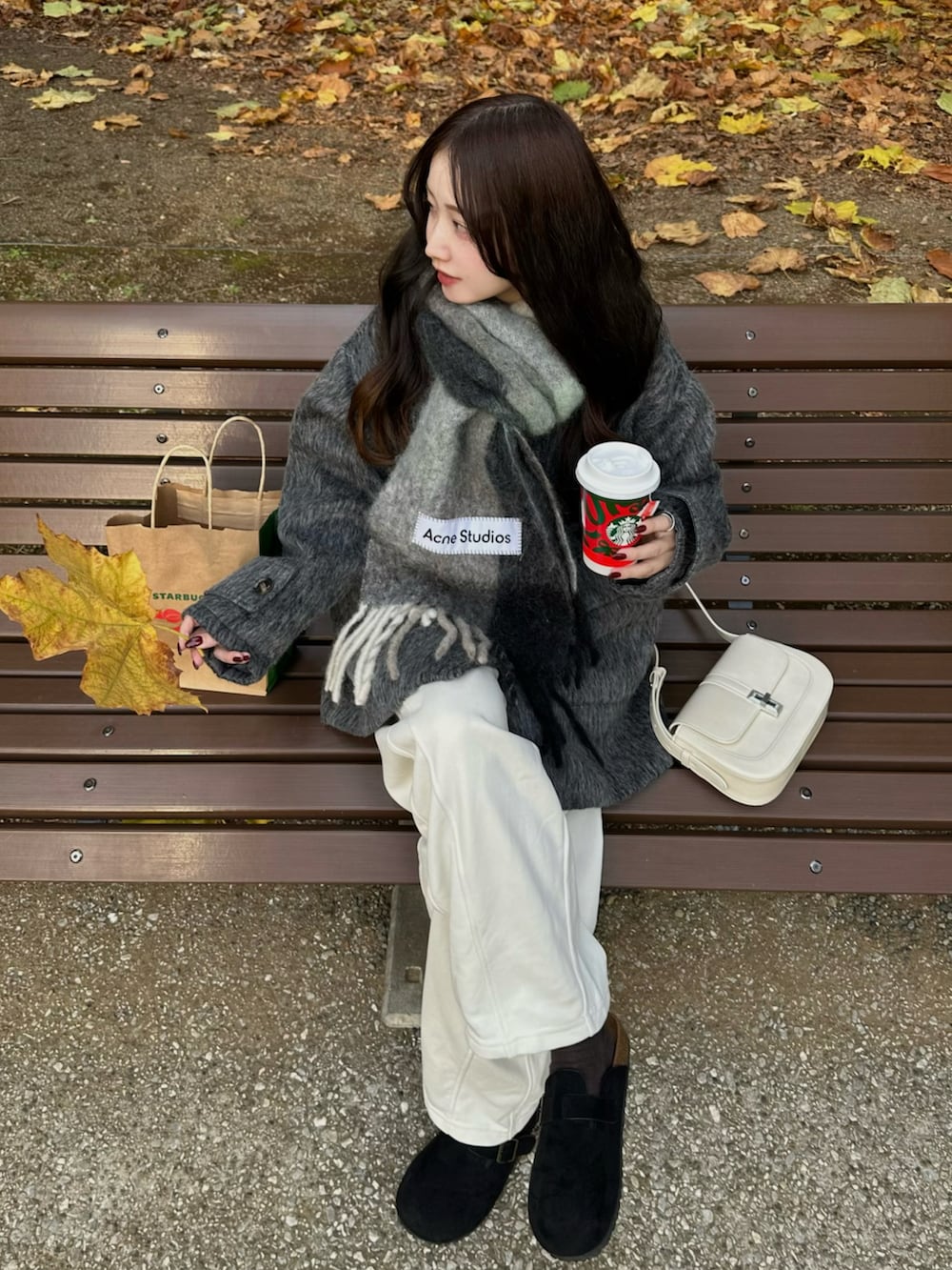 グレー系のステンカラーコート、ホワイト系のスウェットパンツ、グレー系のマフラーを着用したレディースの秋コーディネートの2枚目の写真