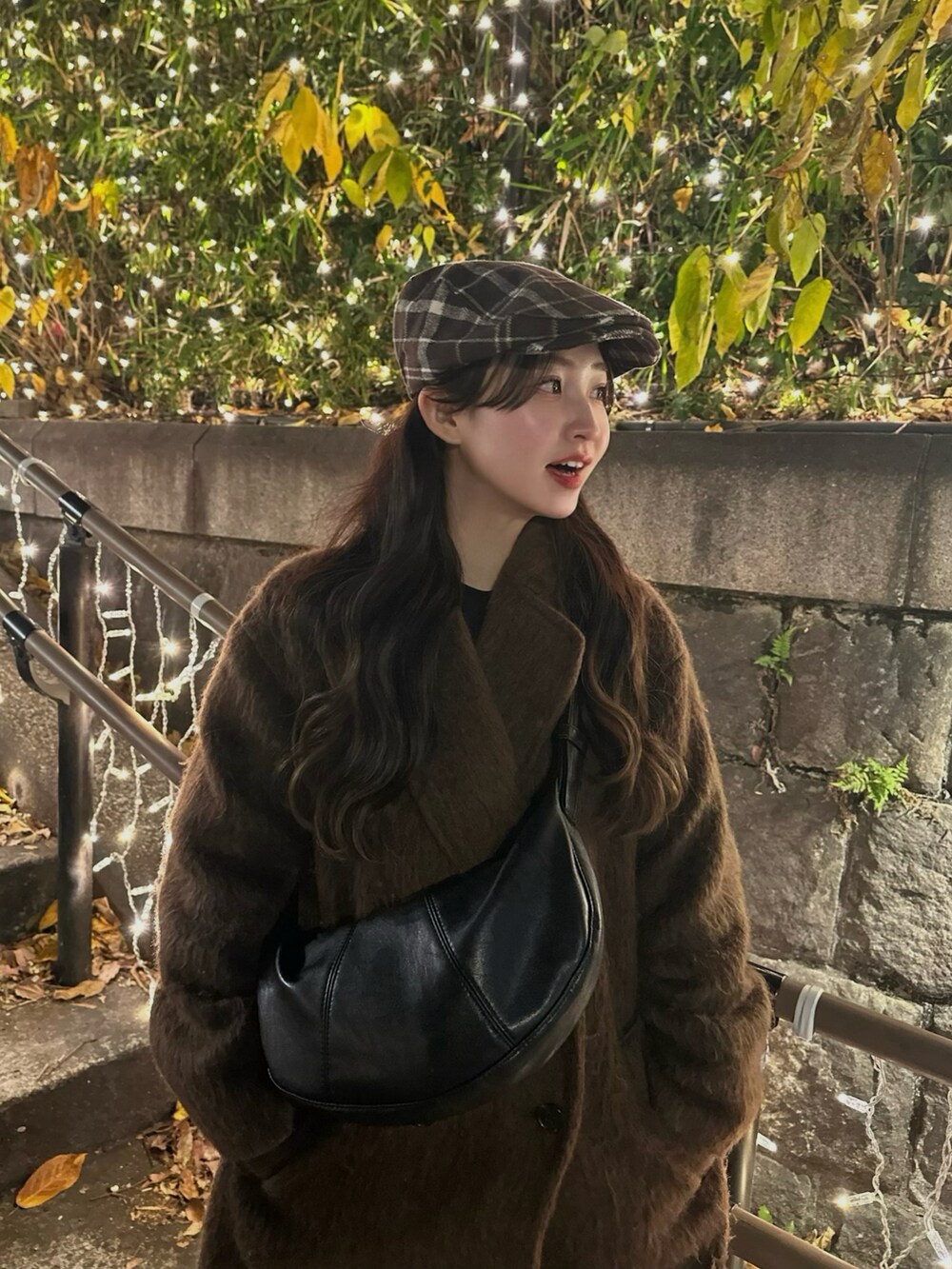 ブラウン系のステンカラーコート、ブラック系のショルダーバッグ、ブラウン系のスニーカーを着用したレディースの冬コーディネートの2枚目の写真