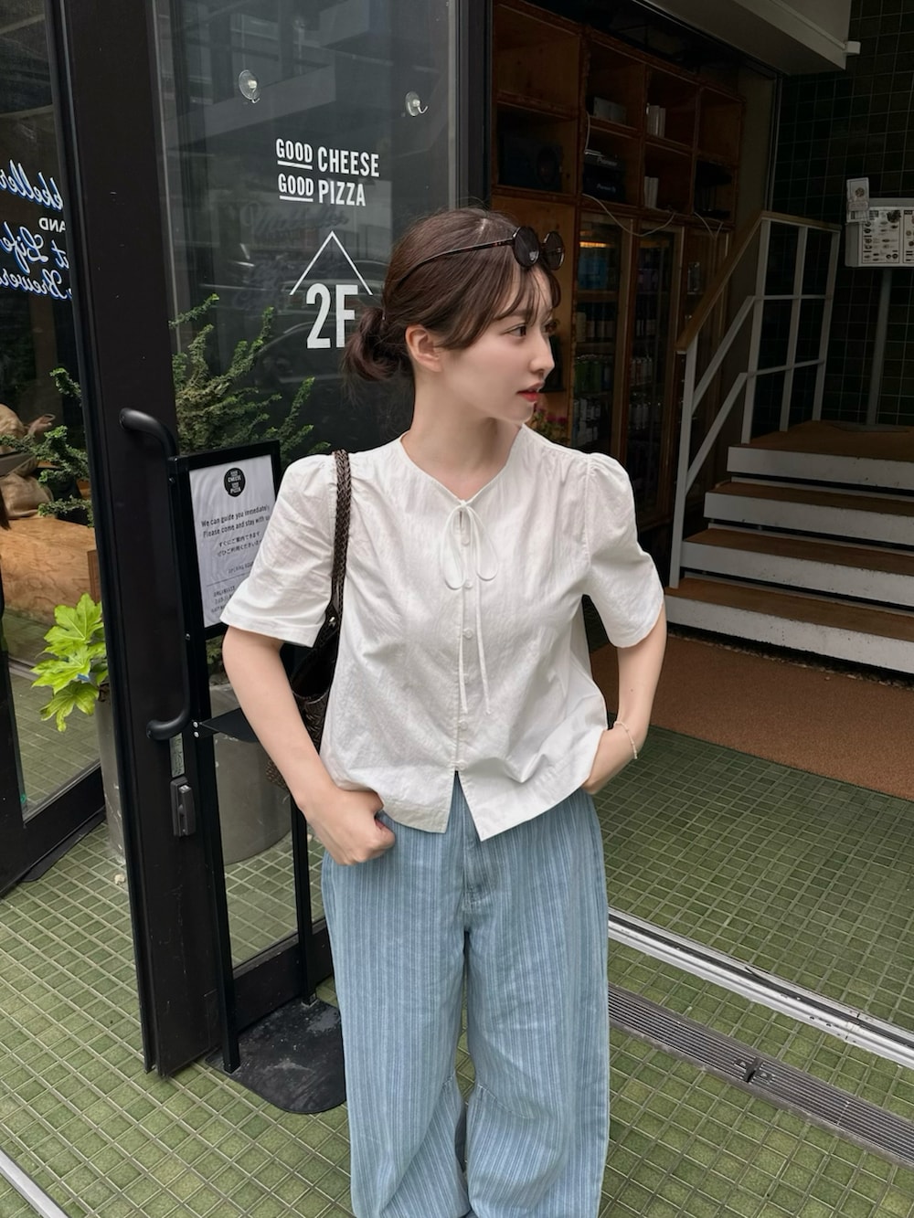 ホワイト系のシャツ/ブラウス、ブルー系のデニムパンツ、ブラウン系のバッグを着用したレディースの夏コーディネートの2枚目の写真