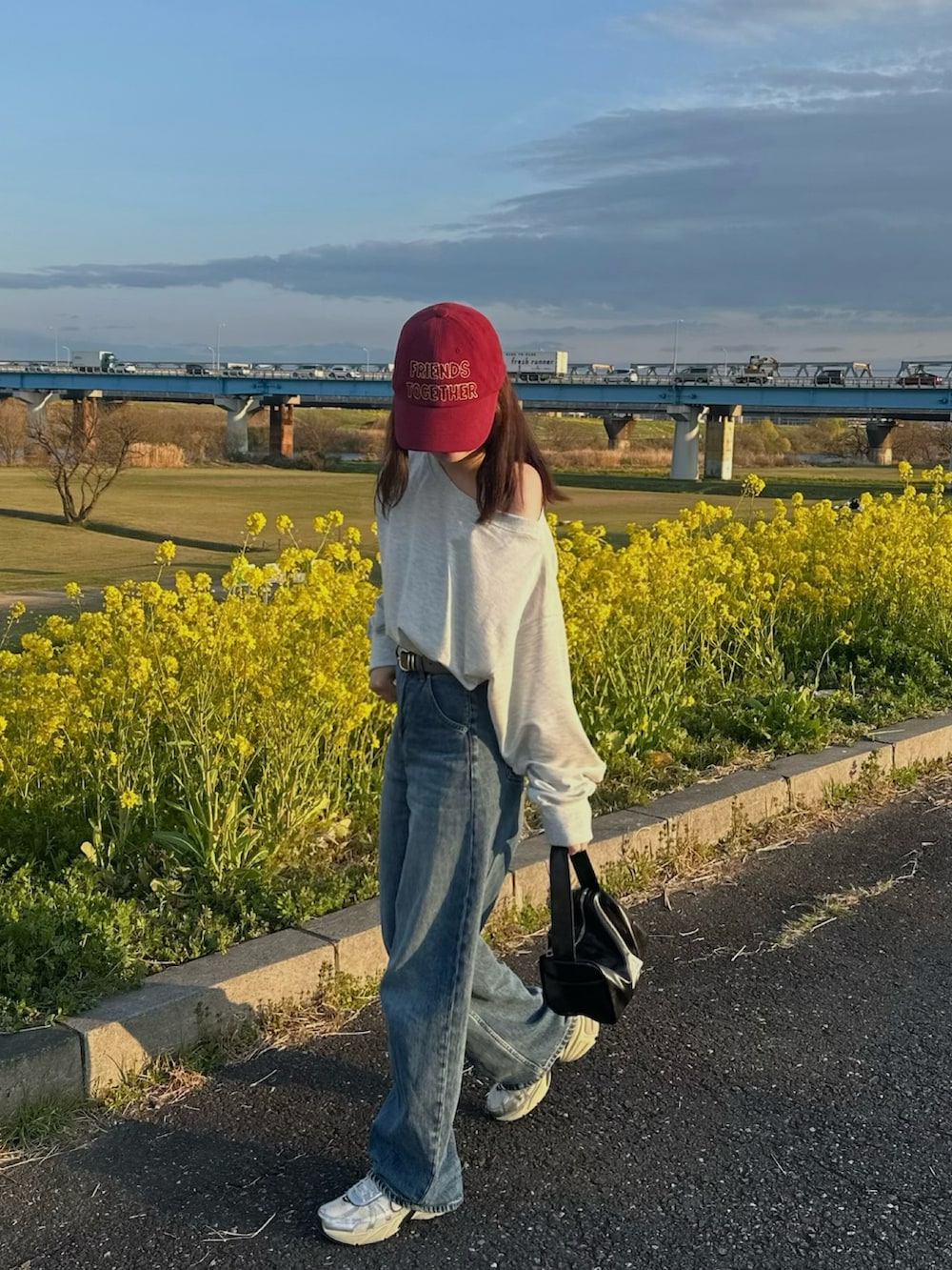 ベージュ系のスウェット、ホワイト系のスニーカー、ブルー系のデニムパンツを着用したレディースの春コーディネートの2枚目の写真