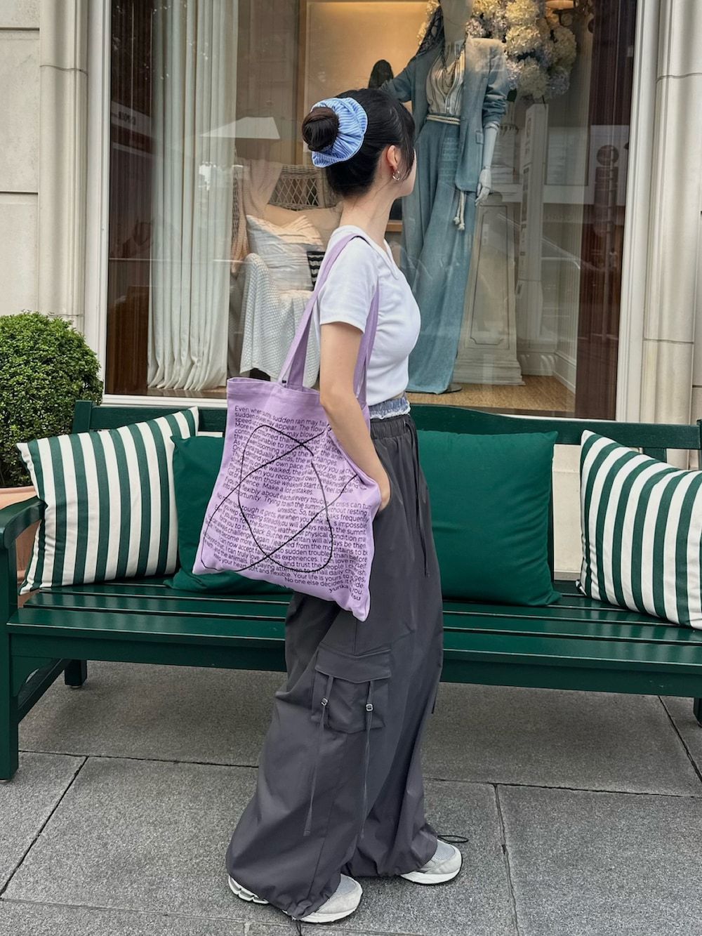 グレー系のカーゴパンツ、ホワイト系のTシャツ/カットソー、パープル系のトートバッグを着用したレディースの夏コーディネートの2枚目の写真