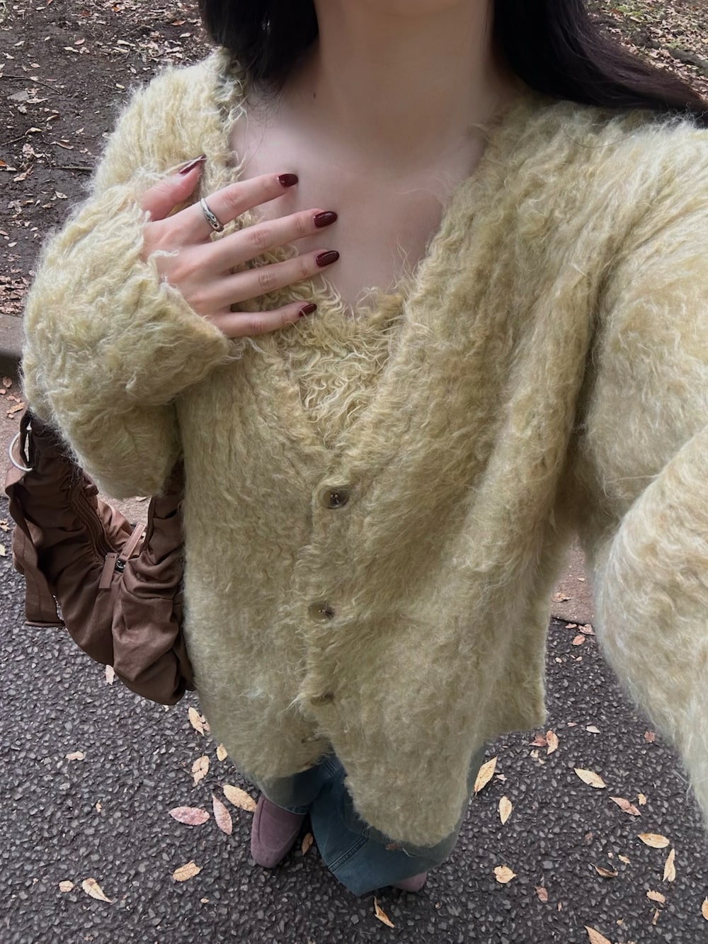 イエロー系のカーディガン/ボレロ、ブルー系のデニムパンツ、ブラウン系のキャップを着用したレディースの秋コーディネートの2枚目の写真