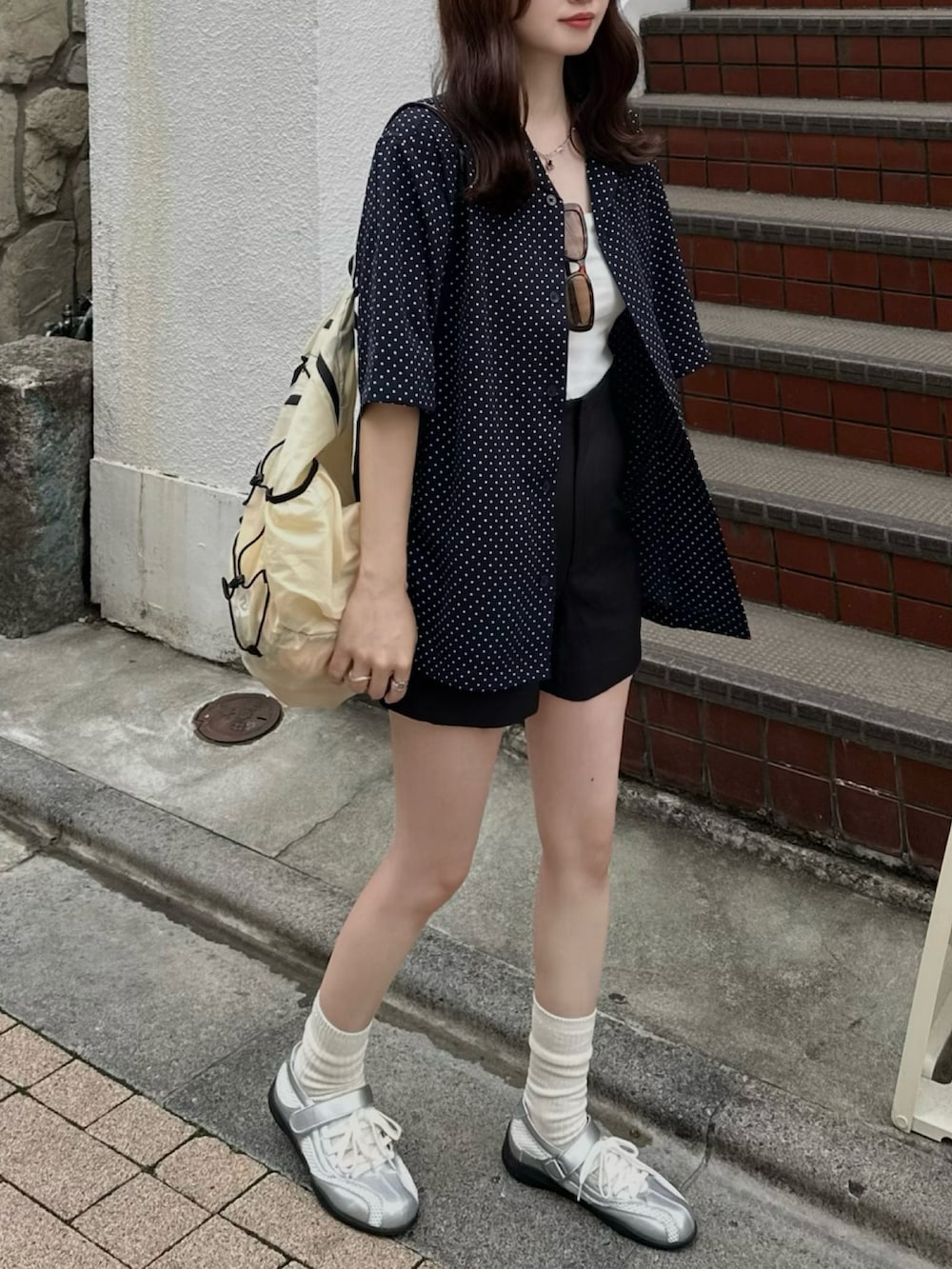 イエロー系のバックパック/リュック、シルバー系のスニーカー、ブルー系のシャツ/ブラウスを着用したレディースの春コーディネートの2枚目の写真