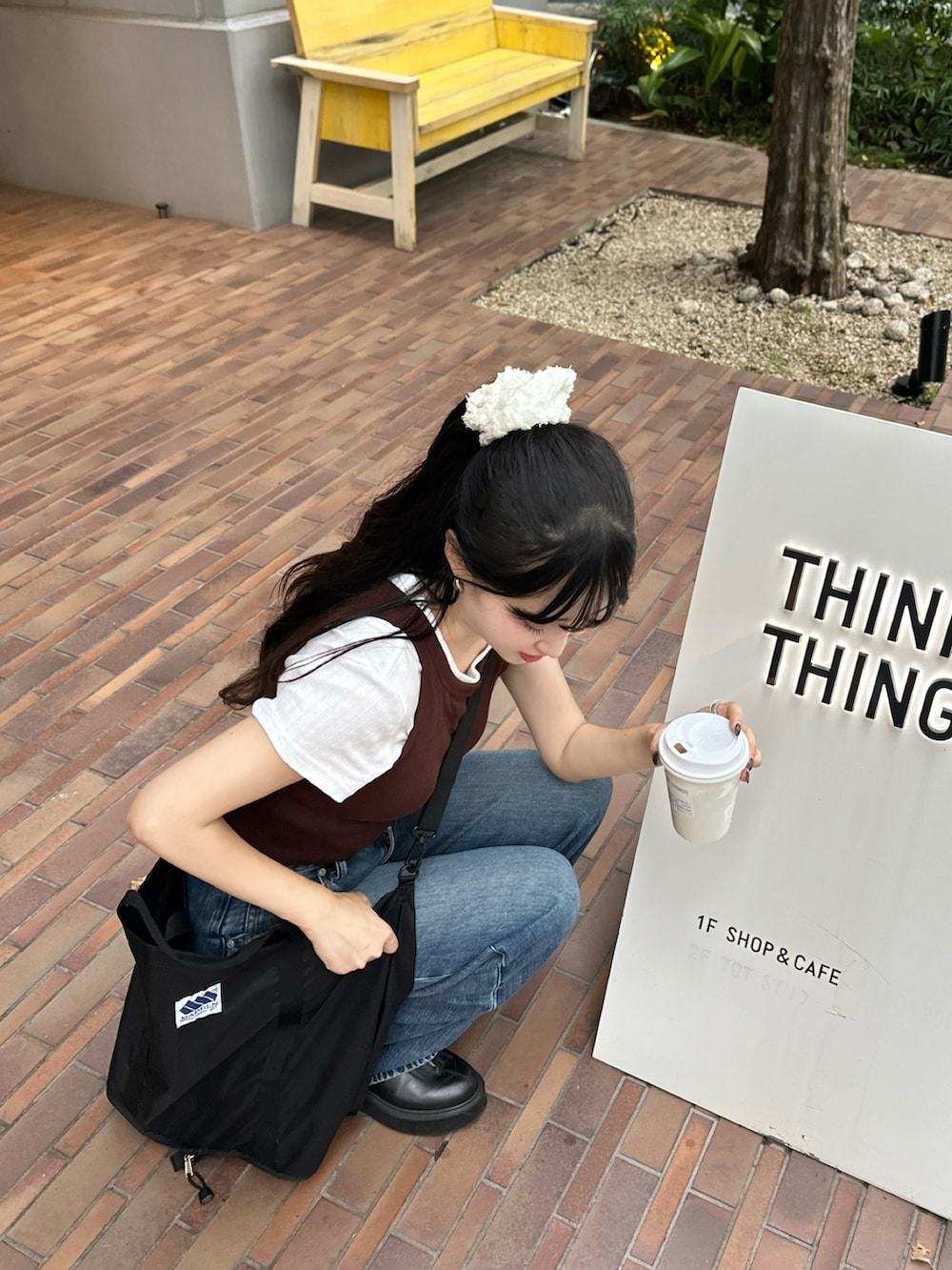 ブラウン系のトップス、ブルー系のデニムパンツ、ブラック系のブーツを着用したレディースの夏コーディネートの2枚目の写真