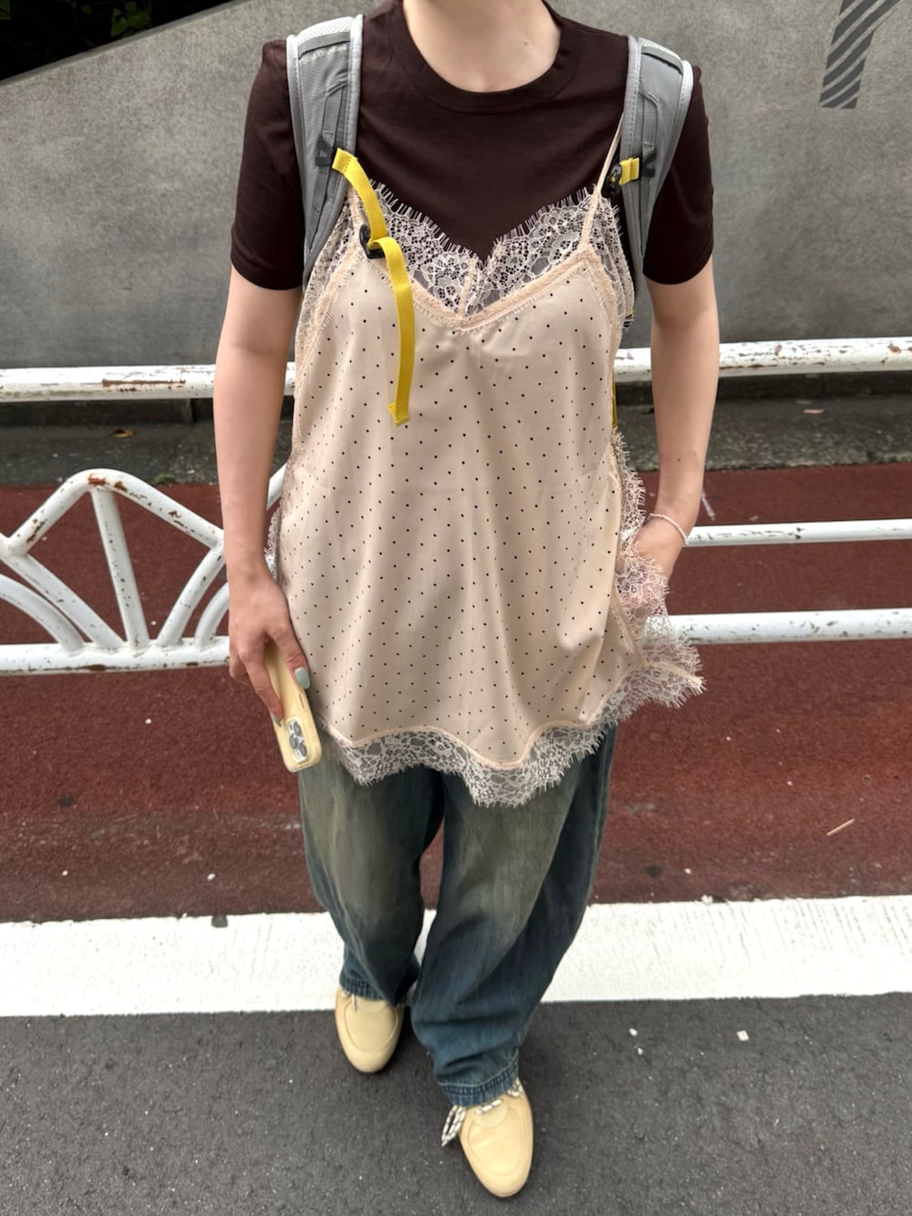 ブルー系のデニムパンツ、グレー系のバックパック/リュック、ベージュ系のキャミソールを着用したレディースの夏コーディネートの2枚目の写真