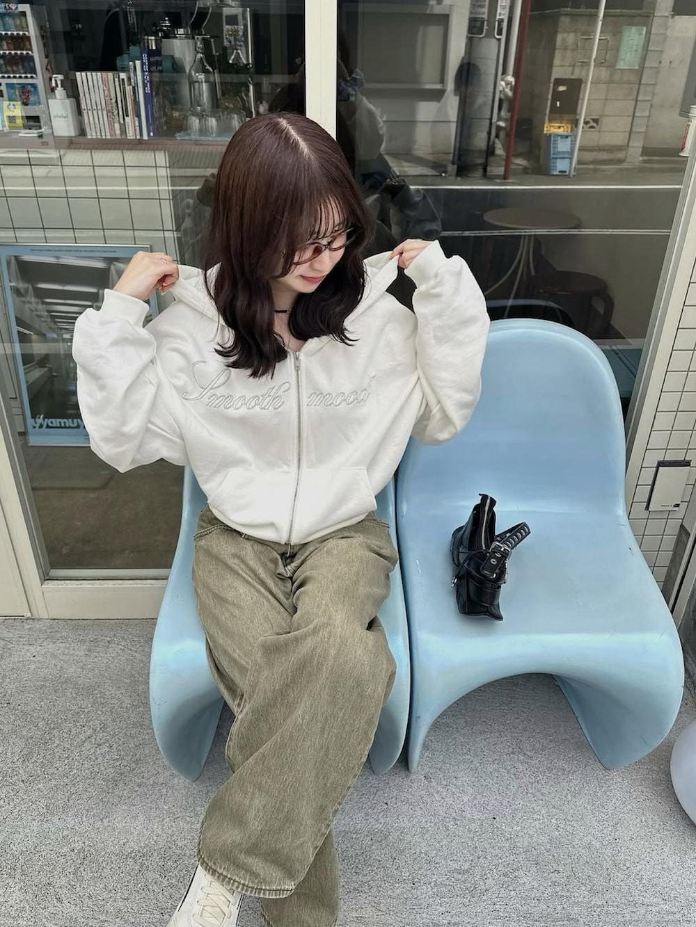 グリーン系のデニムパンツ、ホワイト系のパーカー、ブラック系のバッグを着用したレディースの春コーディネートの2枚目の写真