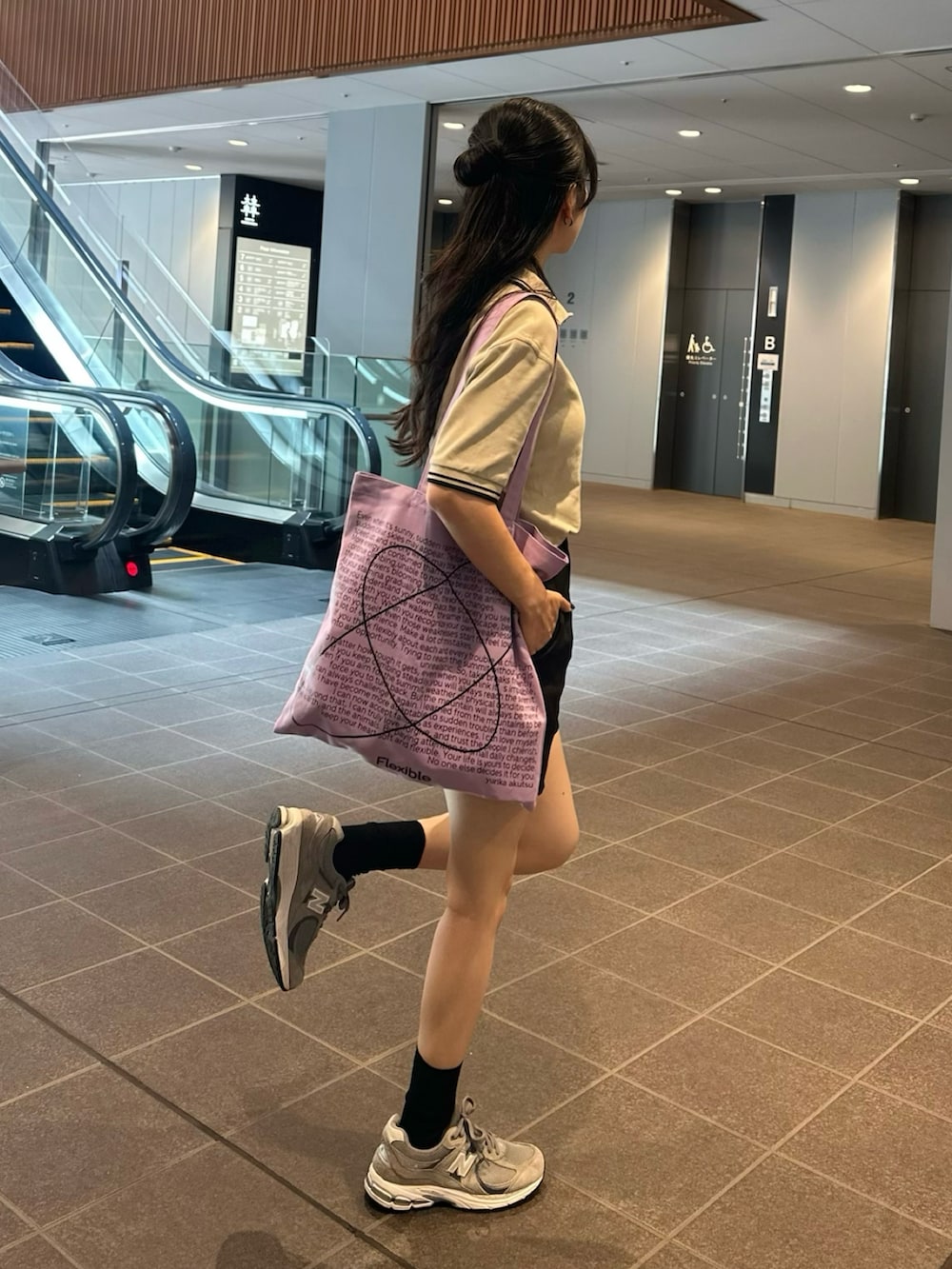 ベージュ系のポロシャツ、ブラック系のパンツ、グレー系のスニーカーを着用したレディースの夏コーディネートの2枚目の写真