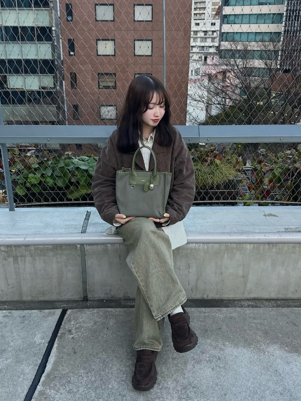 グリーン系のデニムパンツ、ブラウン系のローファー、ブラウン系のジャケット/アウターを着用したレディースの春コーディネートの2枚目の写真