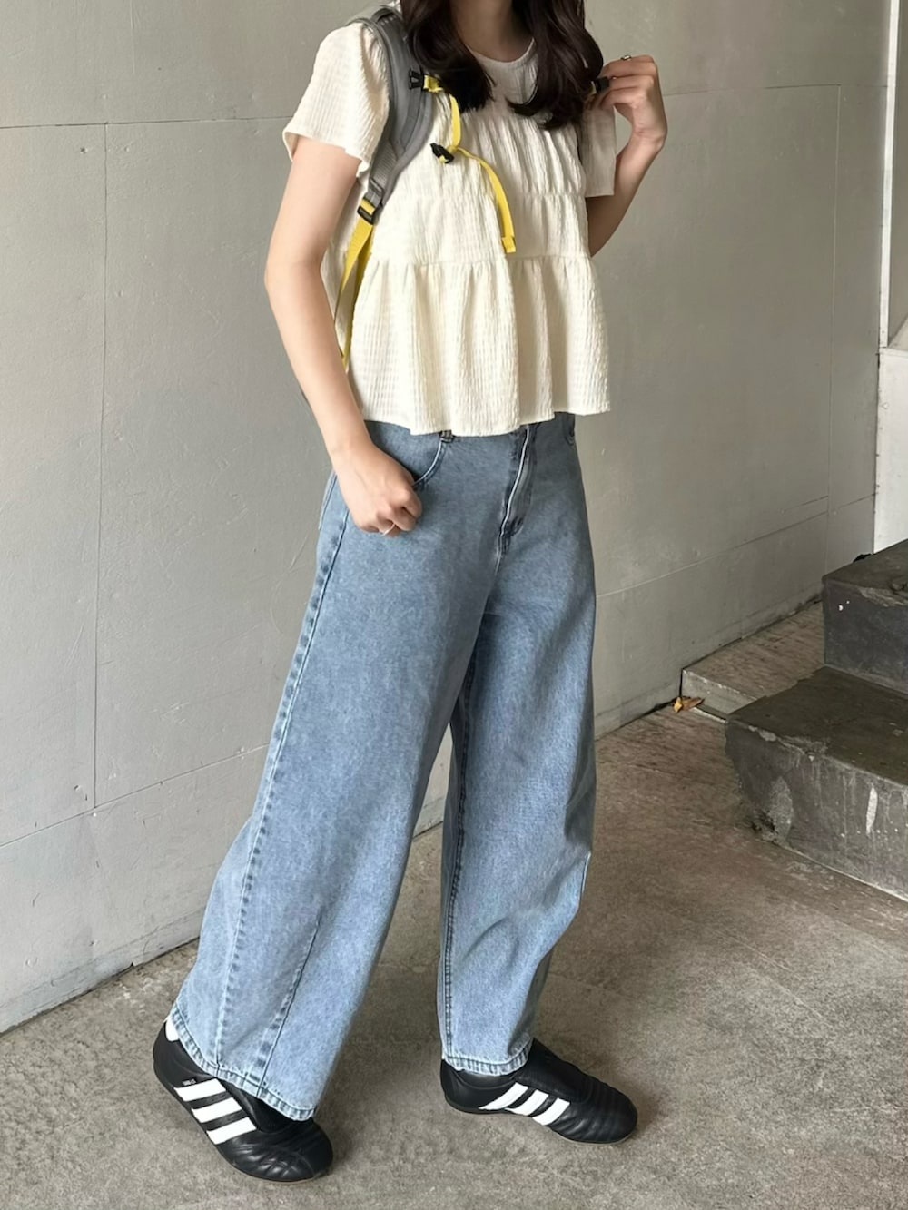 ブラック系のスニーカー、ブルー系のデニムパンツ、グレー系のバックパック/リュックを着用したレディースの春コーディネートの2枚目の写真