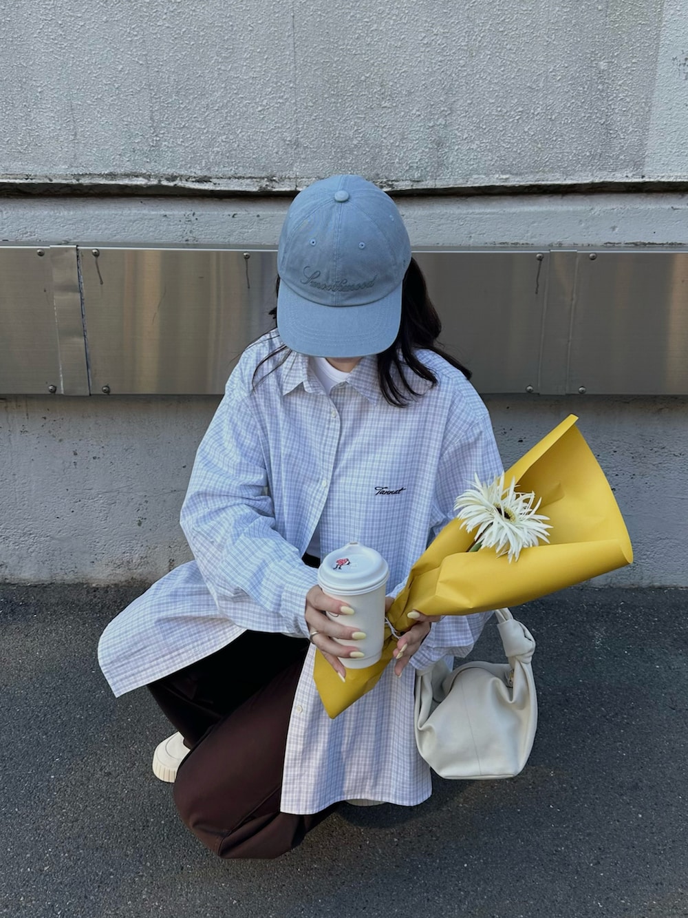 ホワイト系のシャツ/ブラウス、ブラウン系のパンツ、ブルー系のキャップを着用したレディースの春コーディネートの2枚目の写真